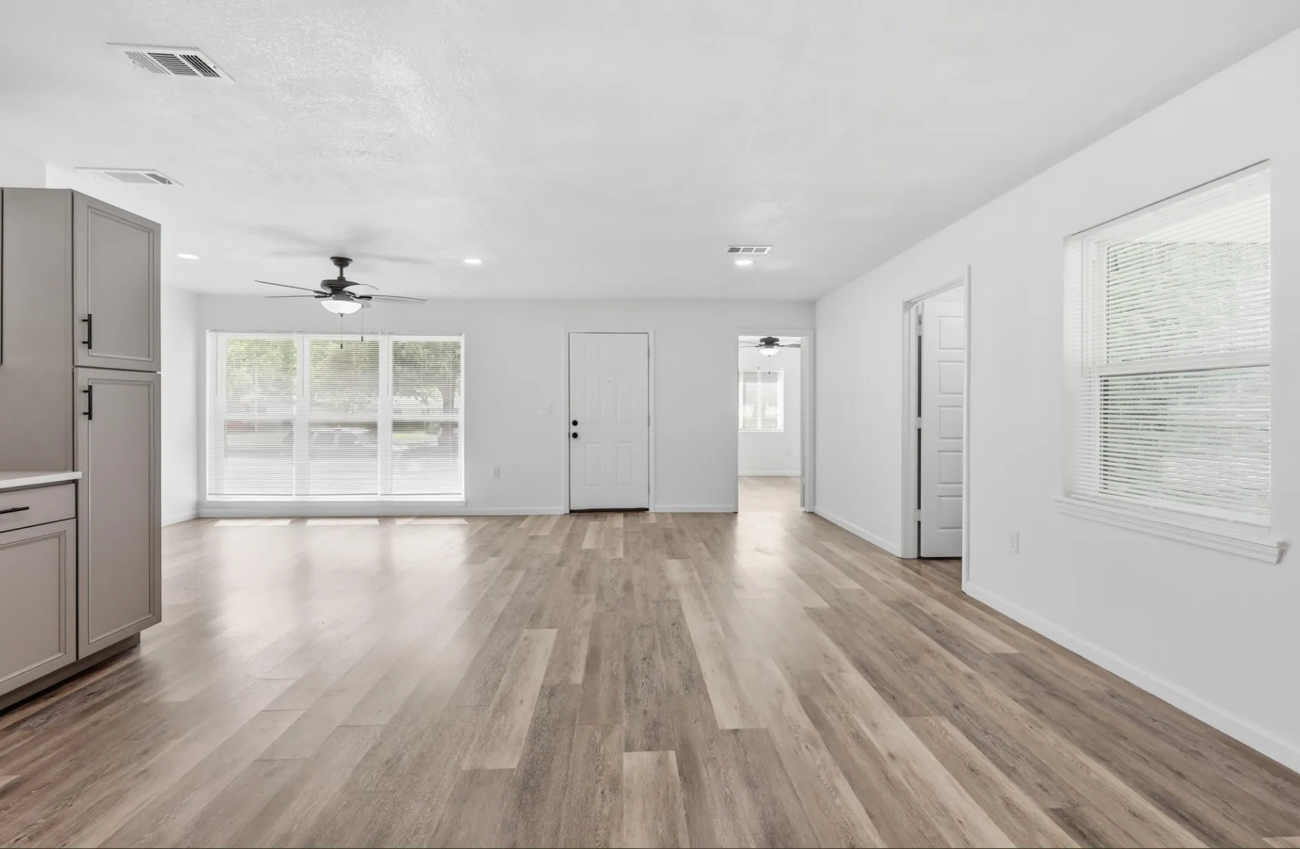 Spacious open-concept living area featuring wood-finish flooring, recessed lighting, and a ceiling fan