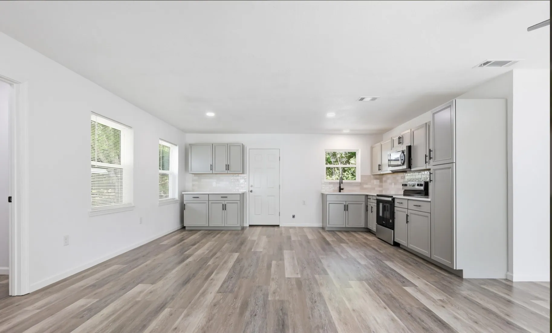 Open-concept kitchen and living area featuring wood-finish flooring, recessed lighting, and white walls