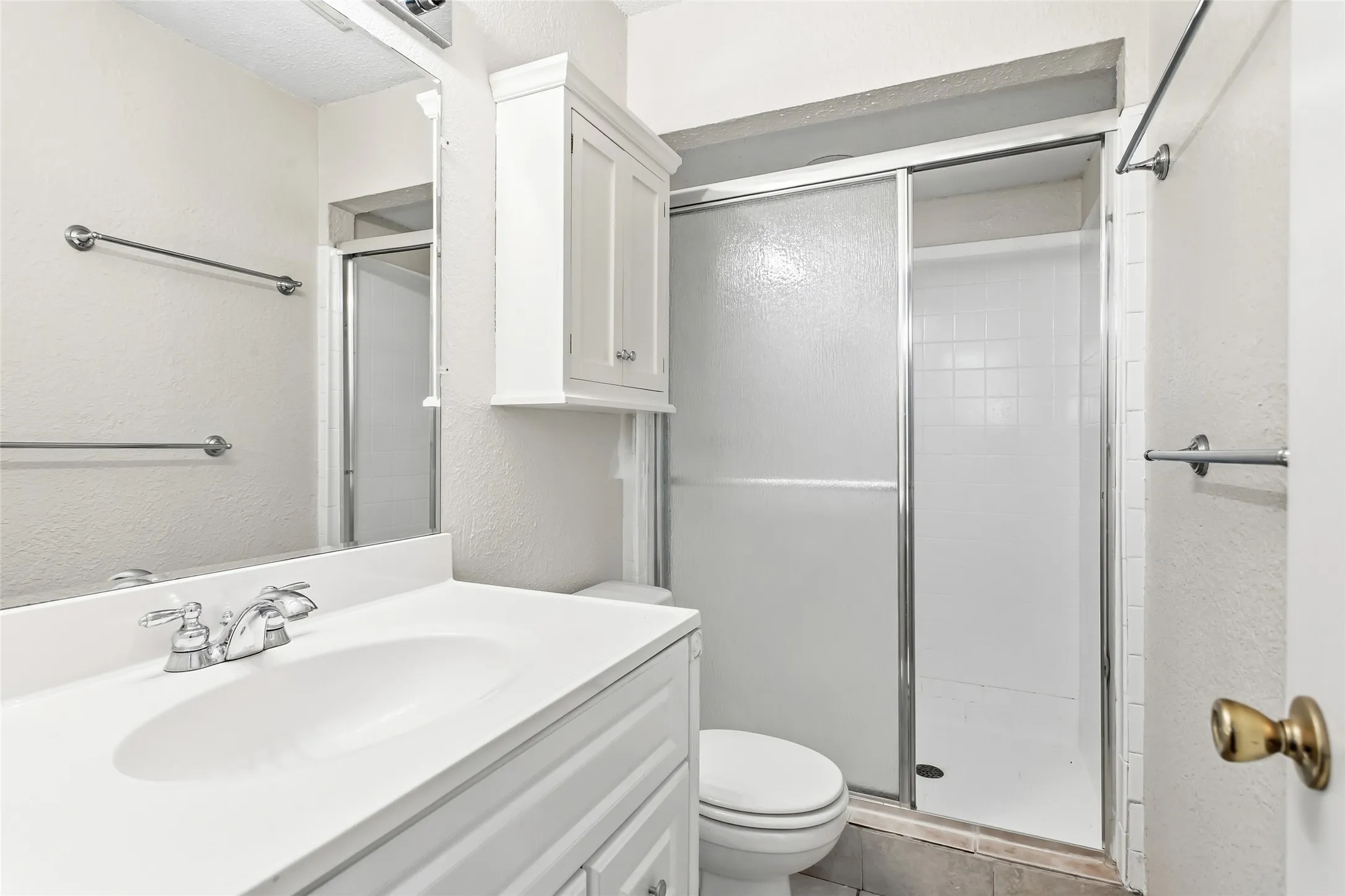 The primary bathroom includes a walk-in shower with sliding glass doors, vanity, and extra storage, creating a practical and comfortable owner's retreat.