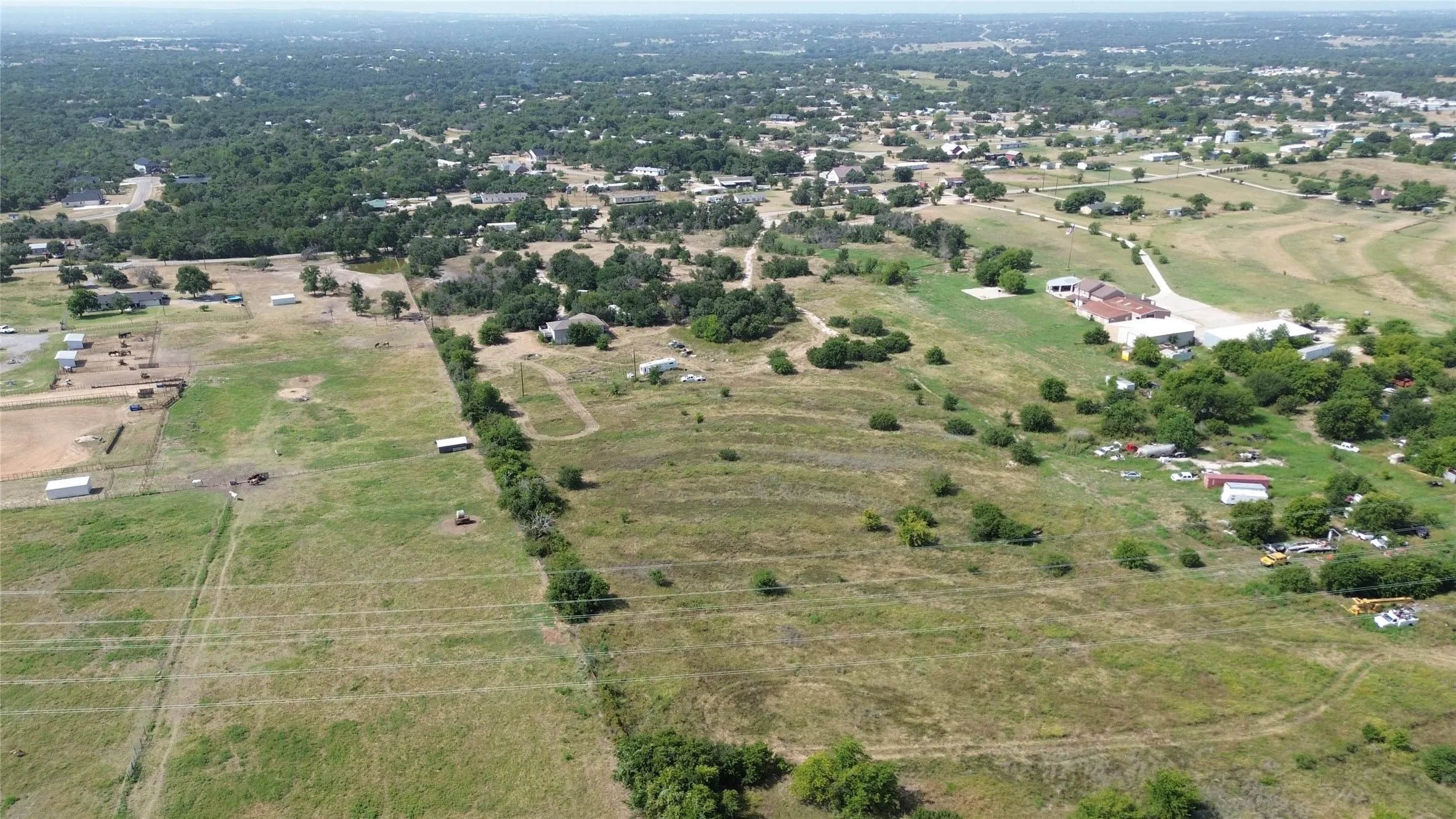Expansive rural acreage featuring varied topography, mature trees, open fields, and multiple outbuildings