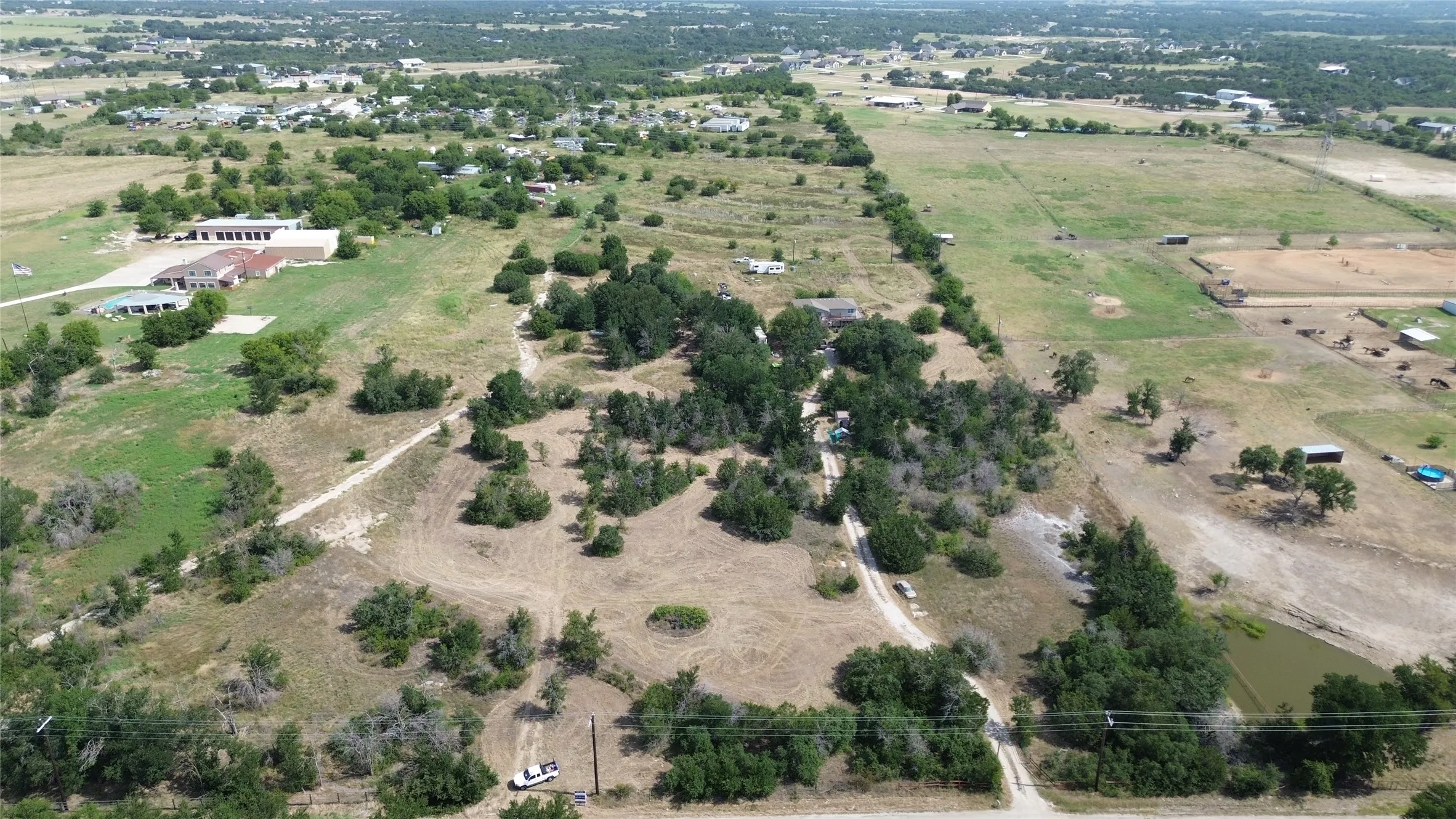 Expansive acreage featuring established trees, an unpaved road, and a pond