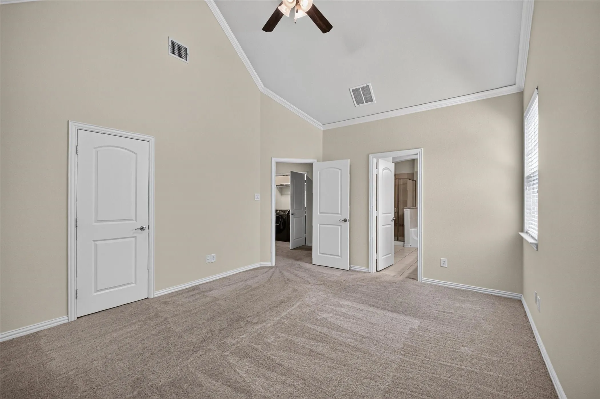 Spacious room featuring vaulted ceilings, a ceiling fan, and neutral-toned carpet