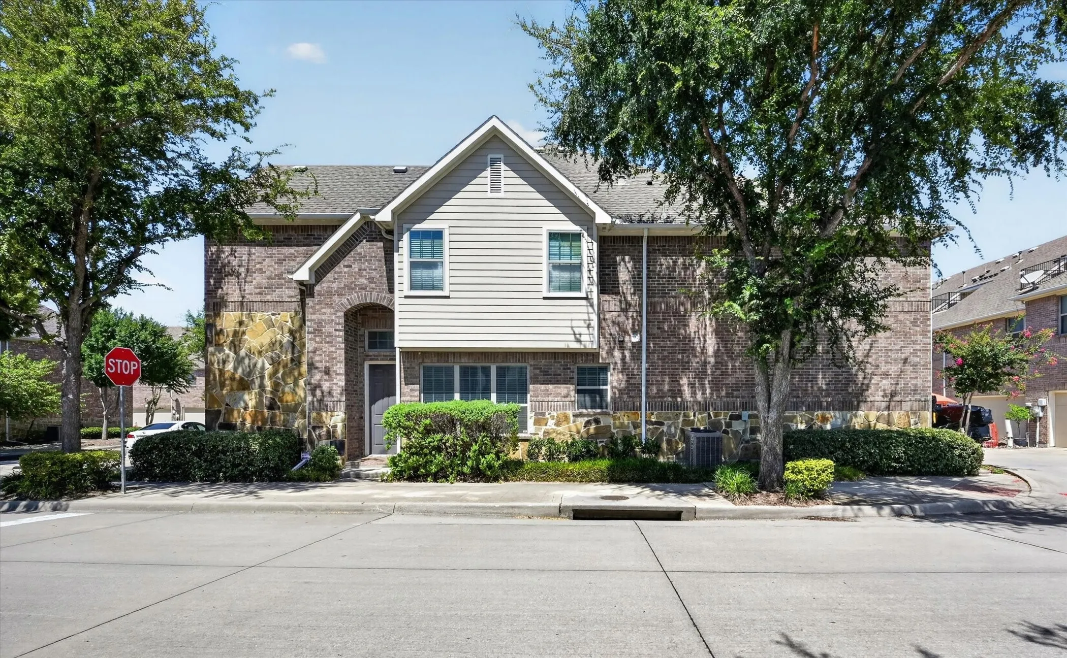 Multi-story property featuring a brick and siding exterior with stone accents