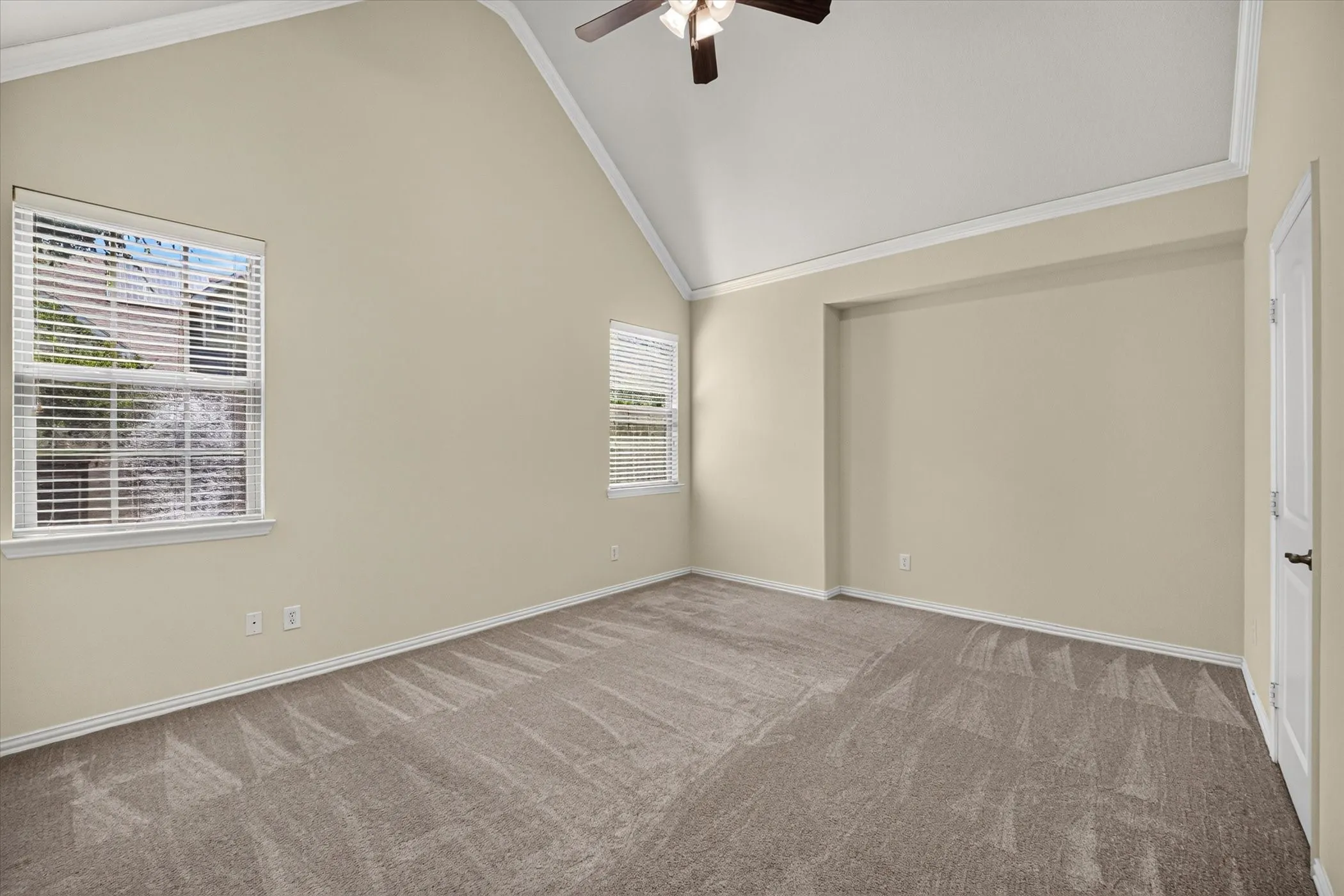 Spacious room featuring vaulted ceilings, neutral-toned walls, and plush carpeting