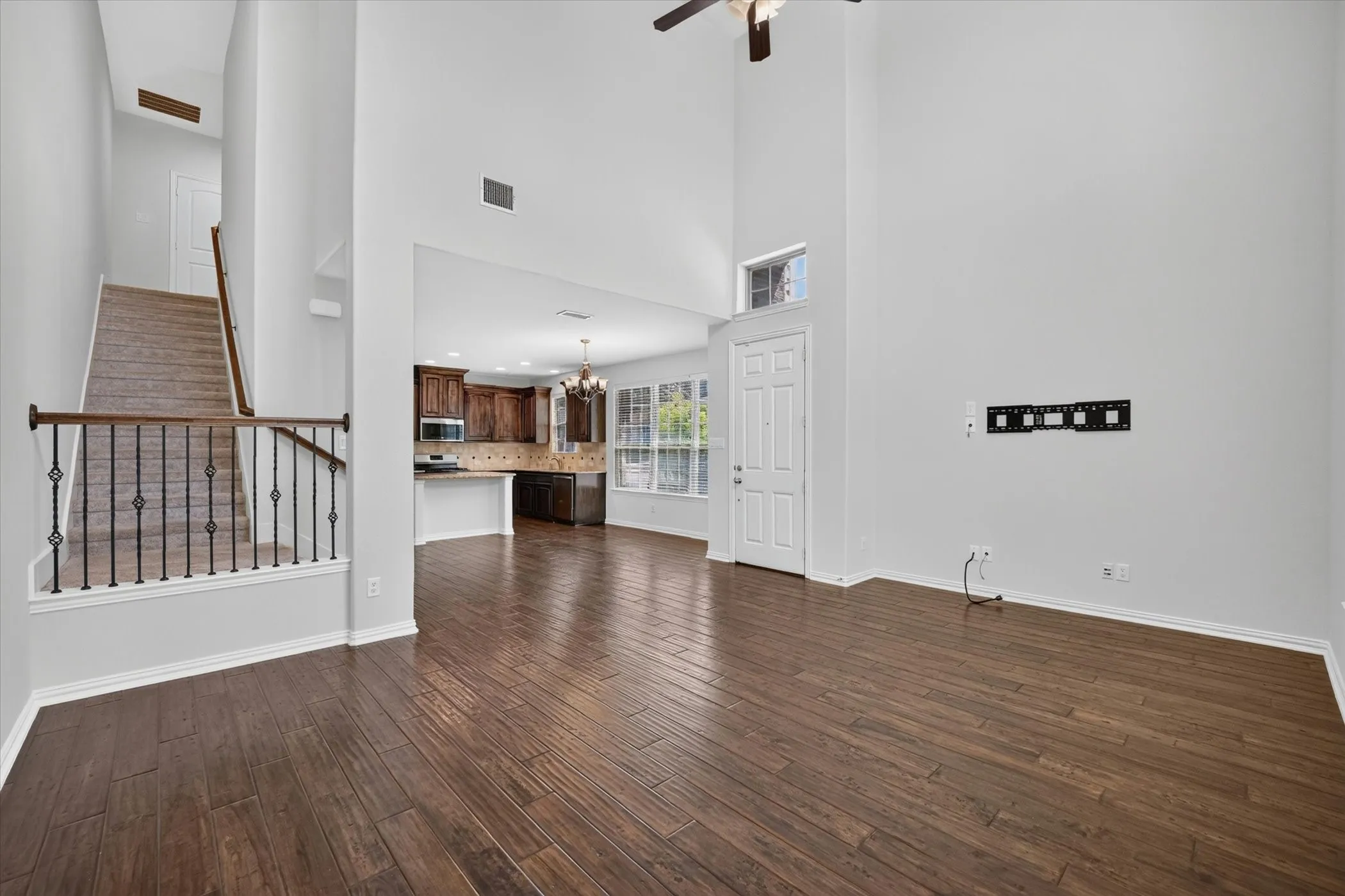 Expansive living area with wood-finish flooring, soaring ceilings, and an open-concept design