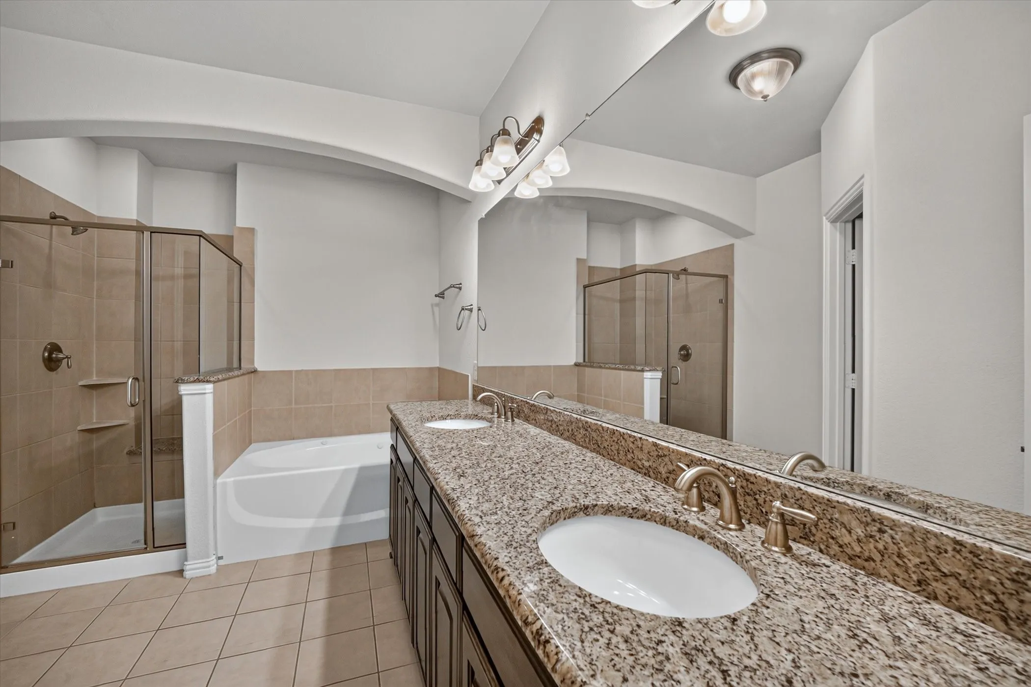 Bathroom featuring a dual vanity with granite-finish countertop, undermount sinks, and bronze-finish fixtures