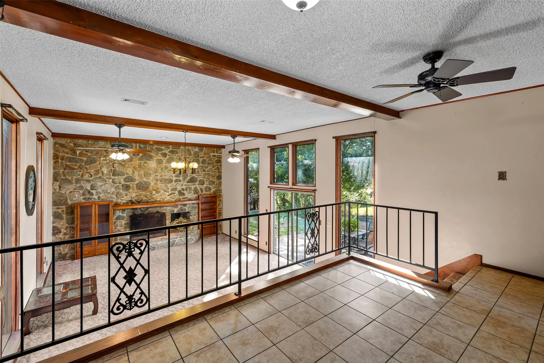  Dining area with view to living area. Railing and vaulted ceiling with exposed beams.