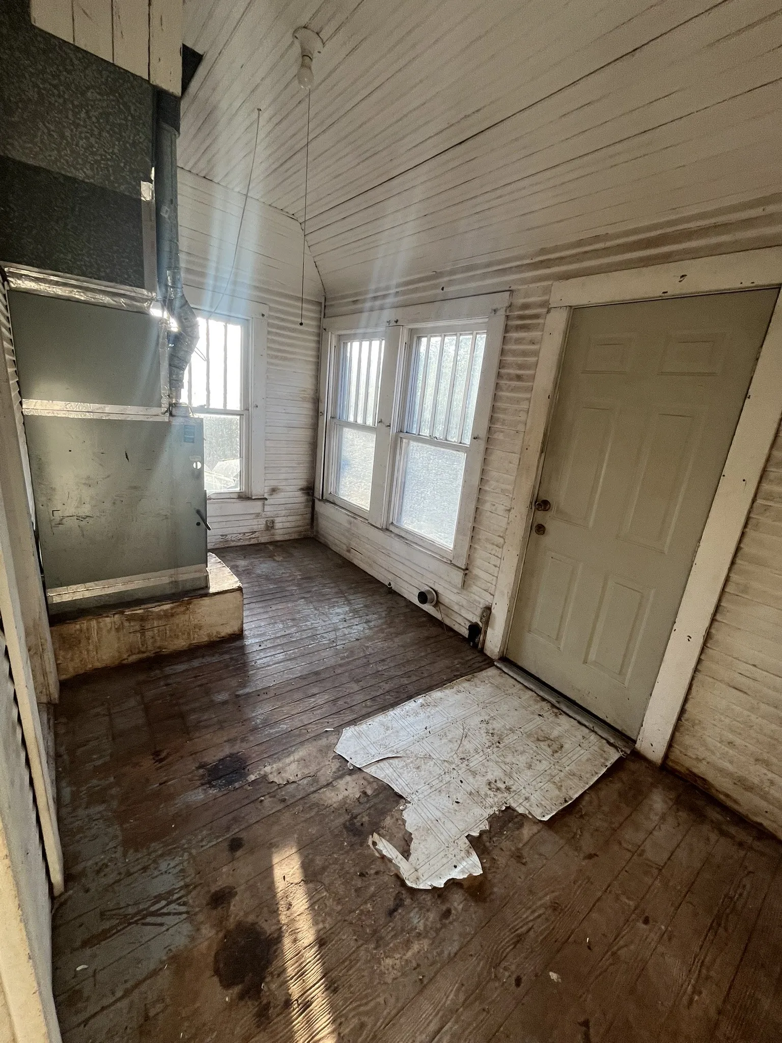 Room featuring natural light from multiple windows, wood-finish flooring, and a ceiling-mounted light fixture