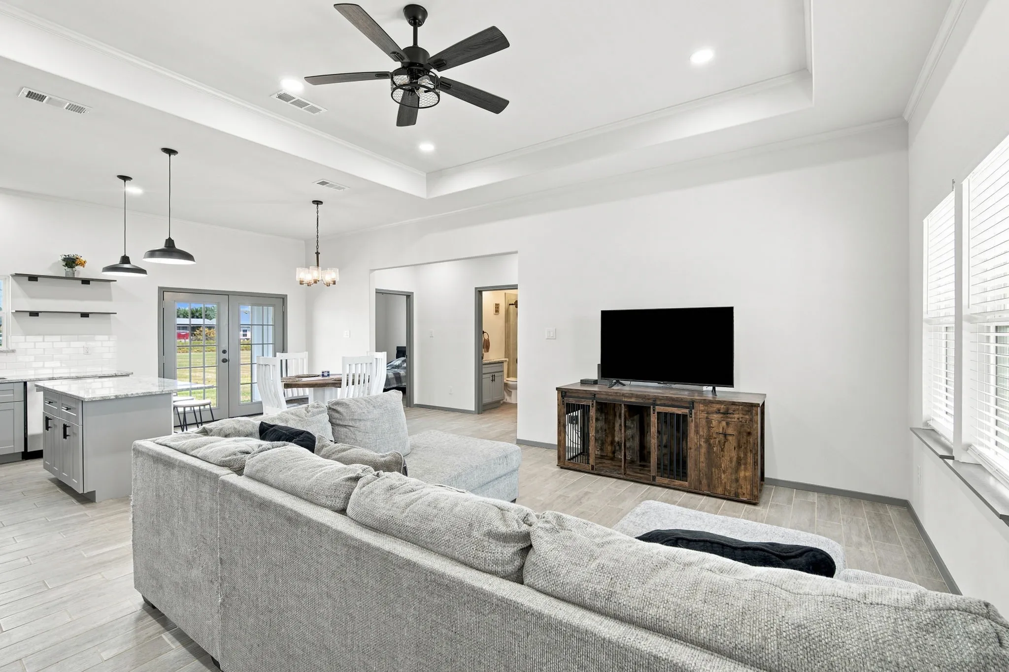 Inviting living room with a tray ceiling and large windows overlooking the yard, a bright and comfortable space to unwind.