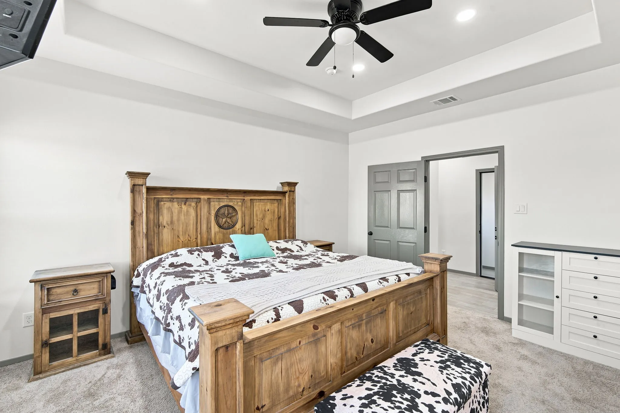 Spacious primary bedroom with a tray ceilings