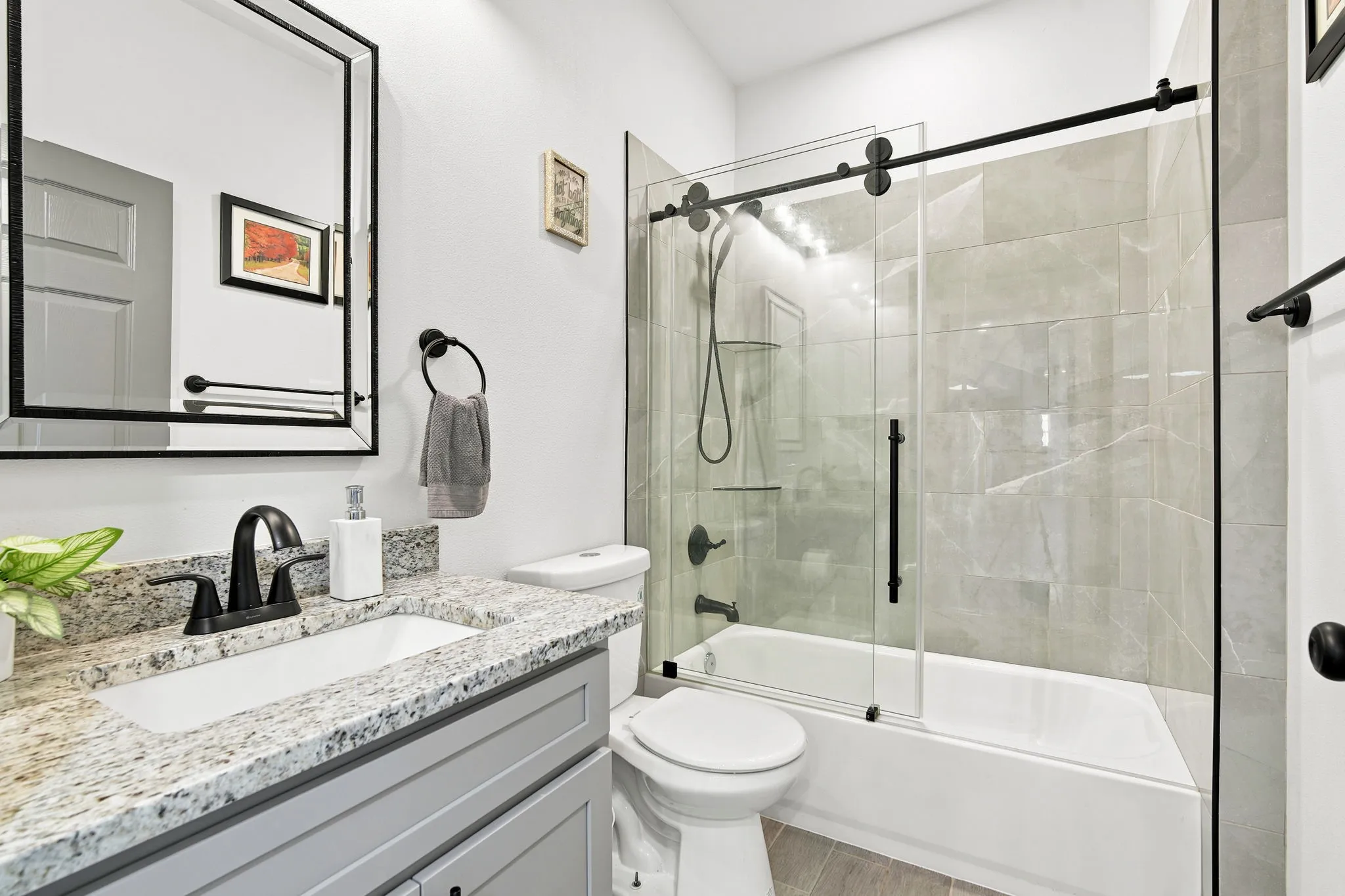 Bathroom featuring a glass-enclosed tub/shower combo and a vanity, both stylish and functional.