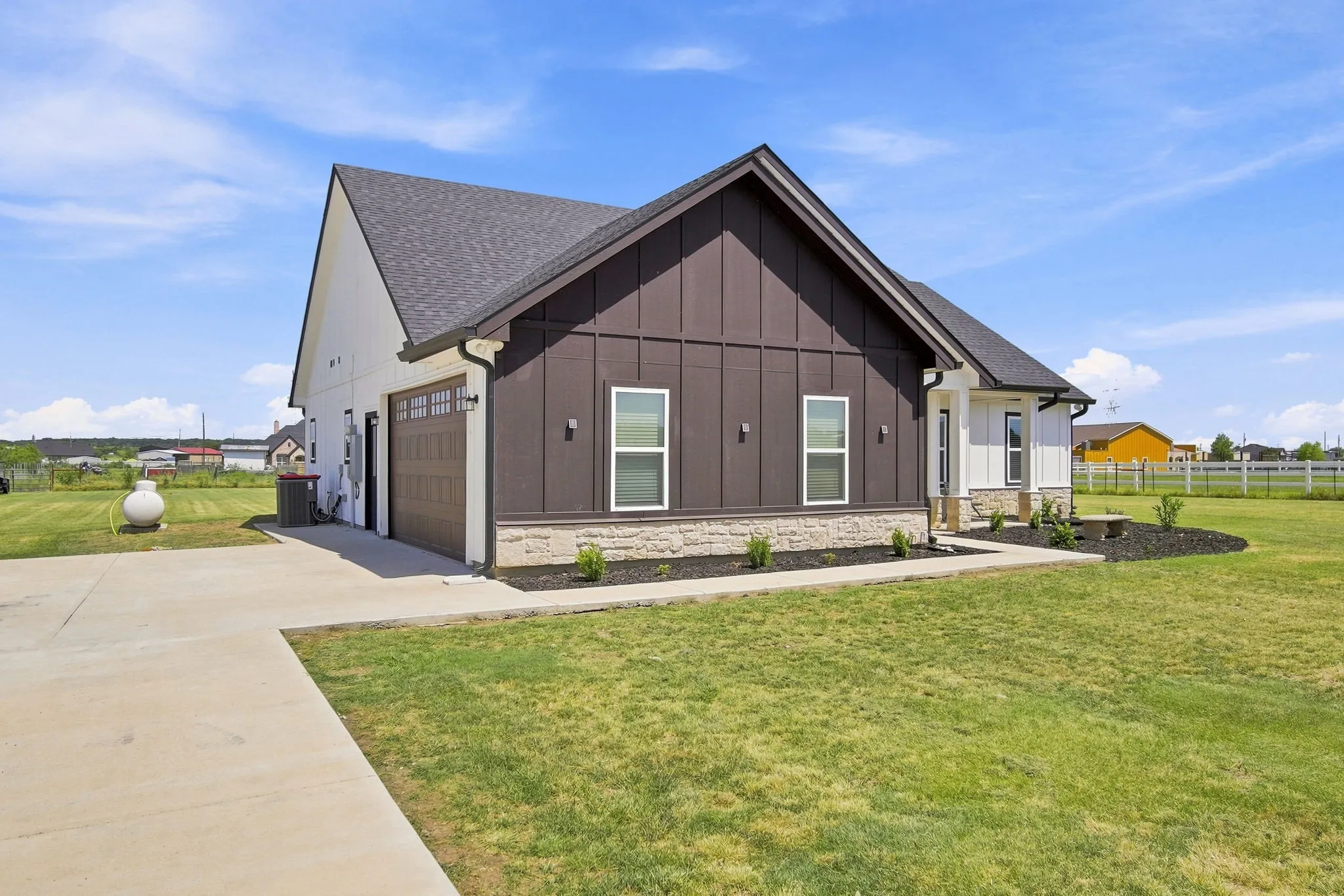 Beautifully maintained exterior featuring modern farmhouse-style architecture, attractive stone accents, a spacious lawn, and a clean, welcoming curb appeal.