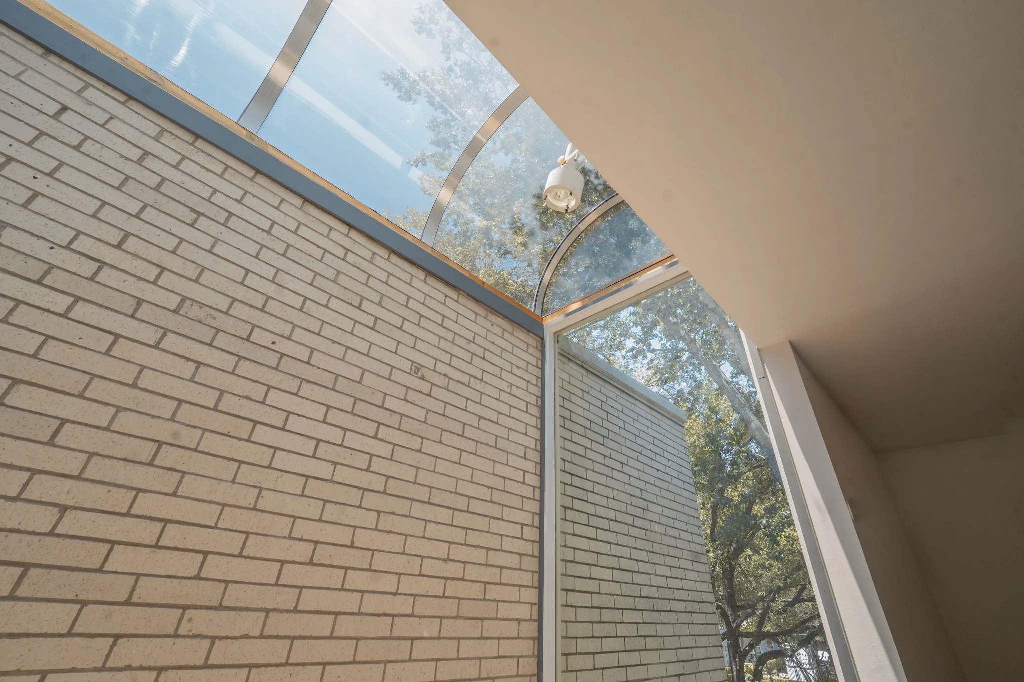 Arched glass skylight and window system with exposed light-colored brick and smooth finished walls
