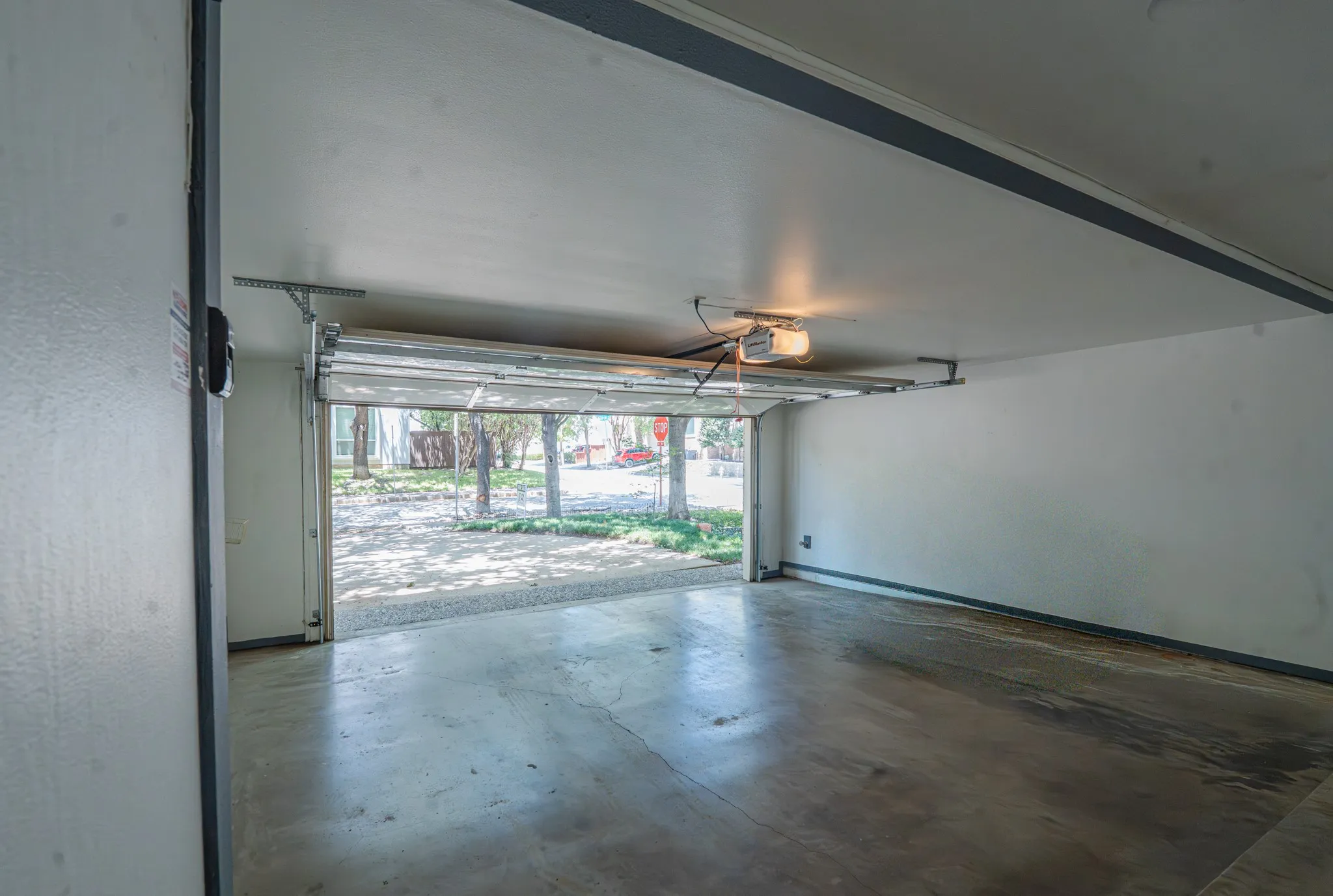 Attached garage with a concrete floor, white painted walls, and an automatic garage door opener