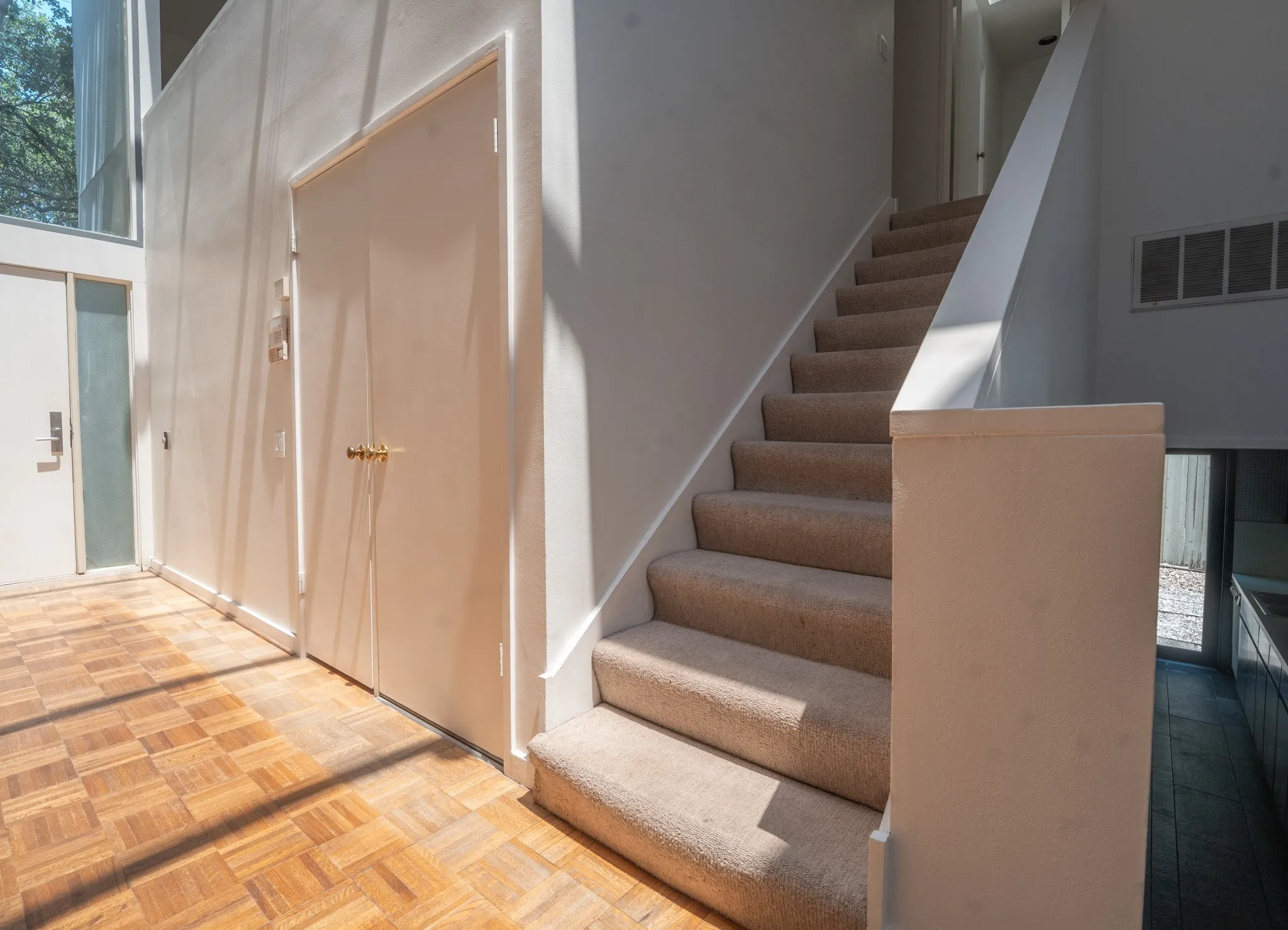 Entryway featuring parquet wood-finish flooring, a carpeted staircase with a white railing, and white walls