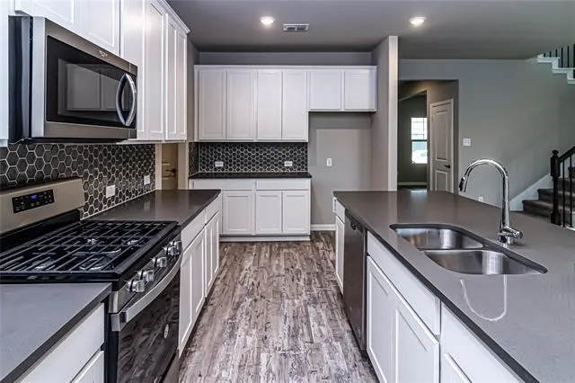 Modern kitchen featuring a central island with an undermount double-basin sink and gooseneck faucet