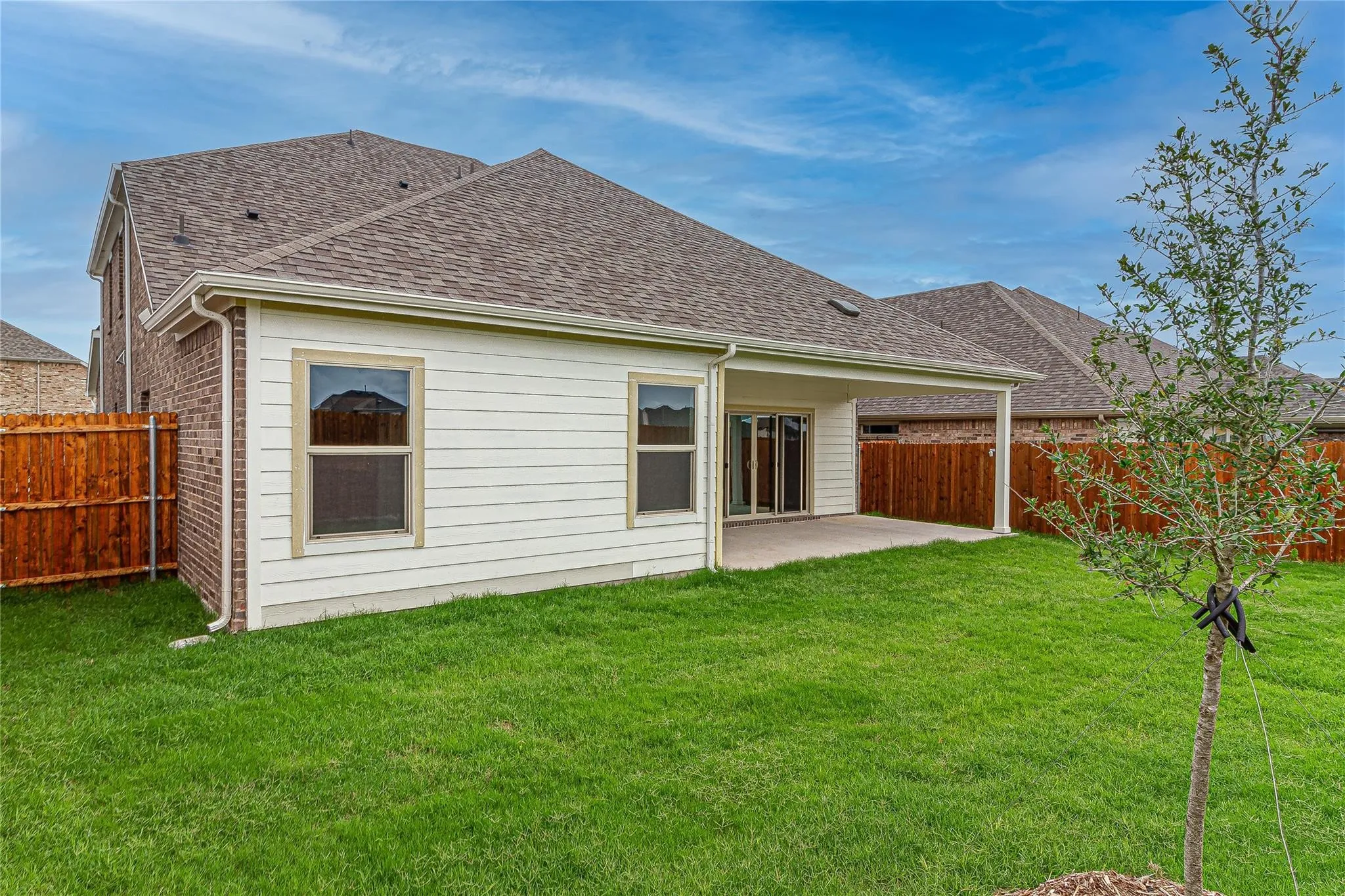 Expansive backyard featuring a covered patio, manicured lawn, and privacy fencing