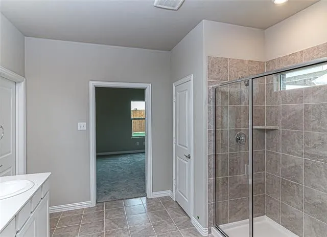 Shower enclosure featuring clear glass panels, a chrome-finish shower head, and an integrated corner shelf
