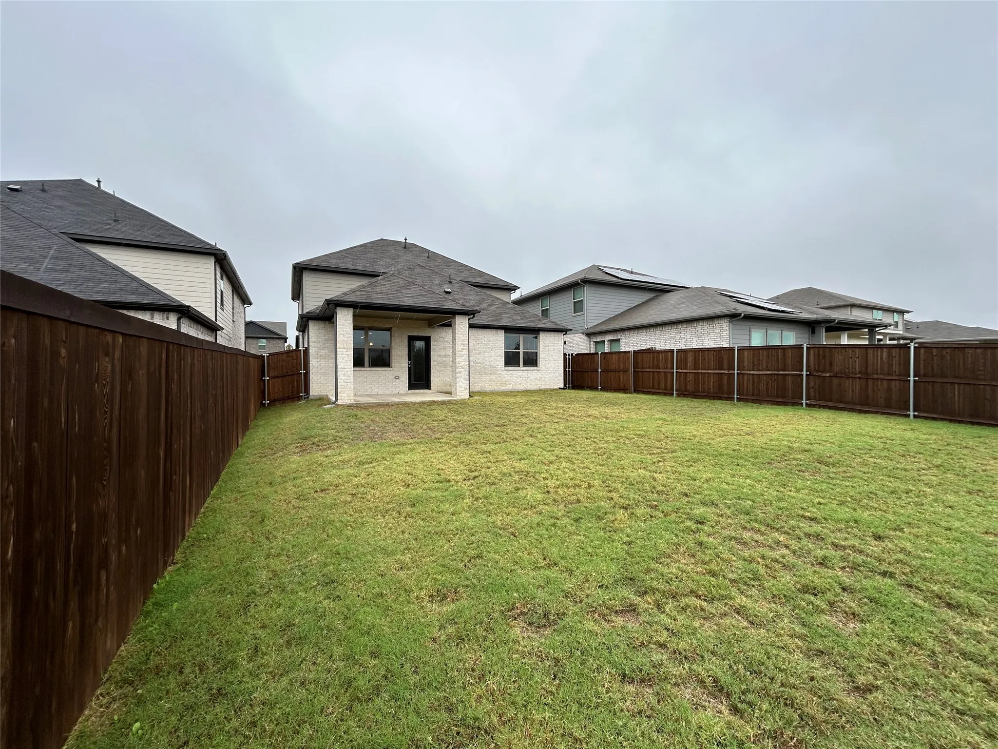 Expansive grassy backyard featuring a full perimeter privacy fence