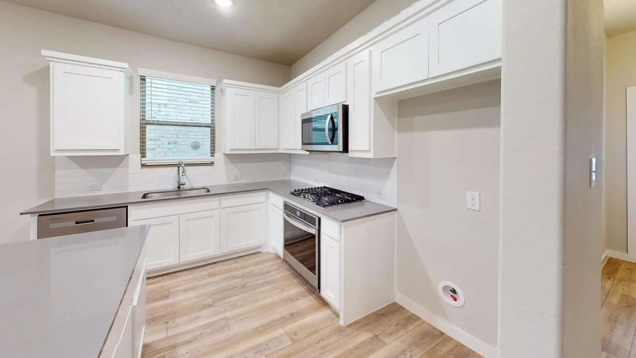 Kitchen featuring white shaker-style cabinetry, light wood-finish flooring, and light-toned countertops