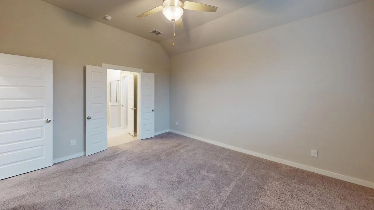 Carpeted interior space featuring a vaulted ceiling and a ceiling fan with integrated lighting