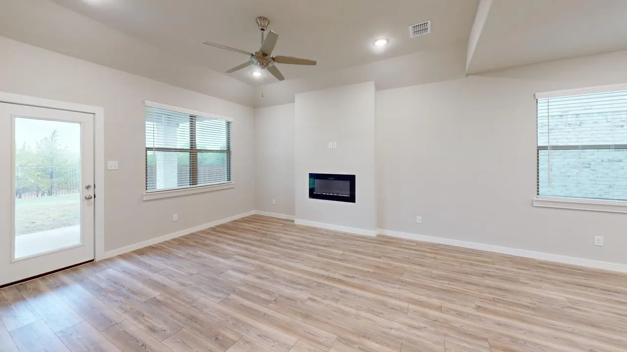 Spacious living area featuring wood-finish flooring, a contemporary electric fireplace, and a ceiling fan