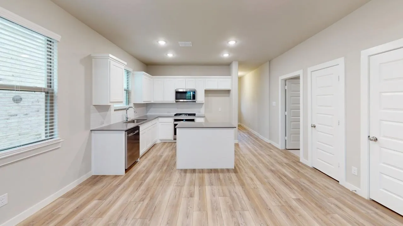 Open-concept kitchen with a central island, recessed lighting, white cabinetry, stainless steel appliances, and light wood-finish flooring