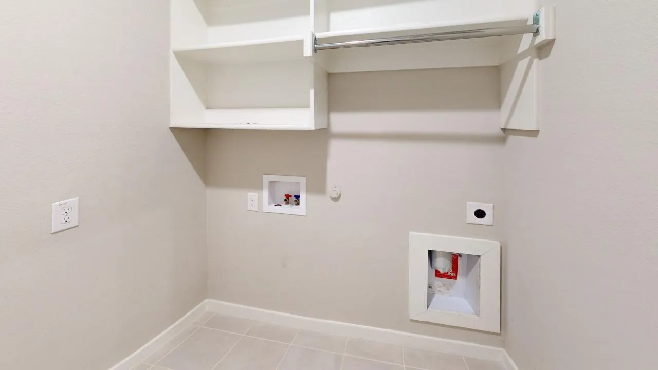 Utility space featuring tile flooring, white wall-mounted cabinetry, a clothes hanging rod, and dedicated appliance hookups