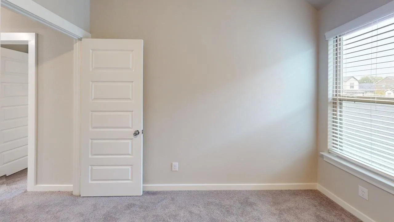 Bedroom featuring neutral carpeting, light-toned walls, and a multi-paneled door