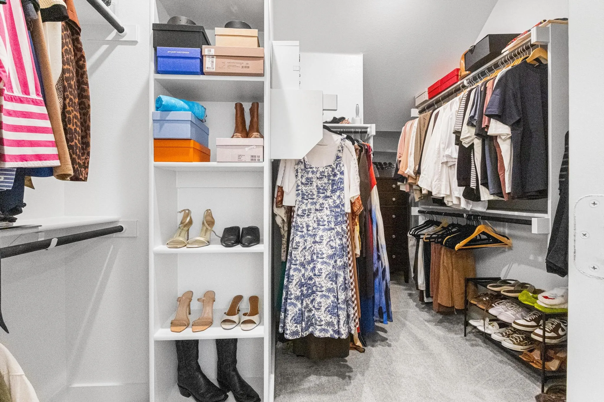 Walk-in closet featuring built-in shelving, multiple hanging rods, and sloped ceiling architecture