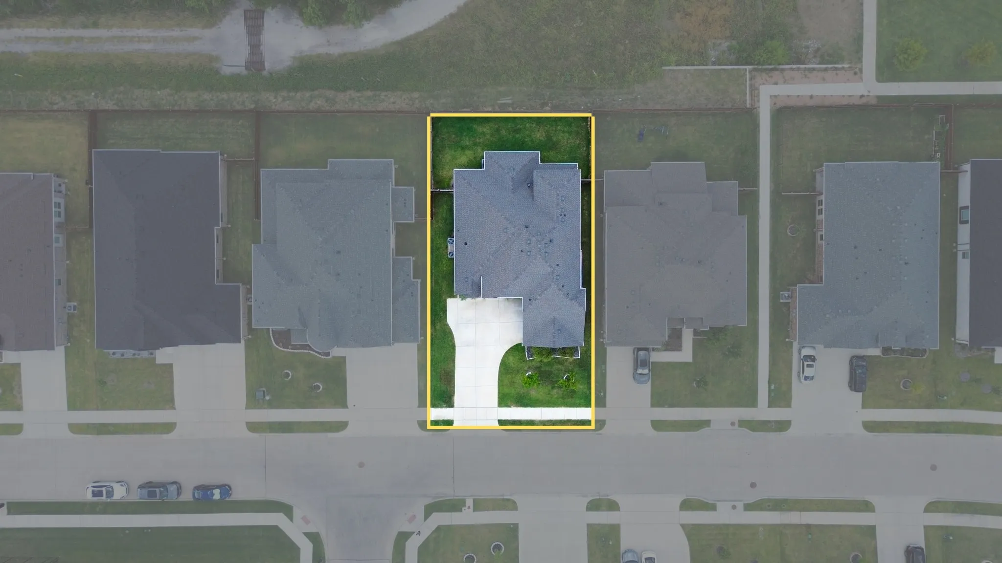 Aerial perspective showcasing a residential property with a dark shingle roof and a concrete driveway