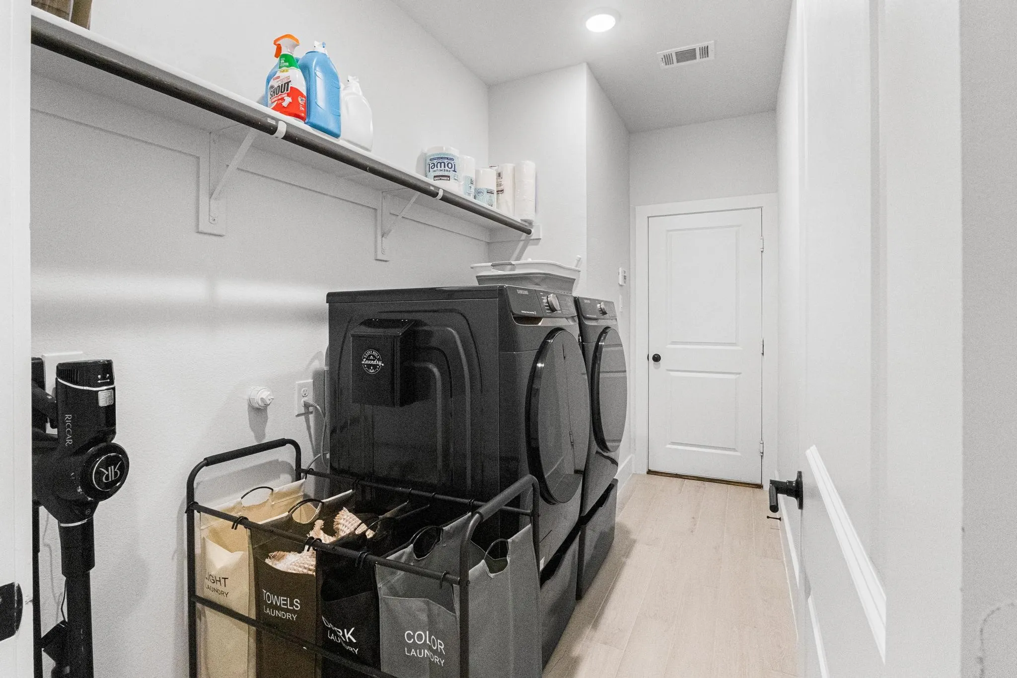 Dedicated laundry area featuring a light wood-finish floor, white walls, and a recessed ceiling light