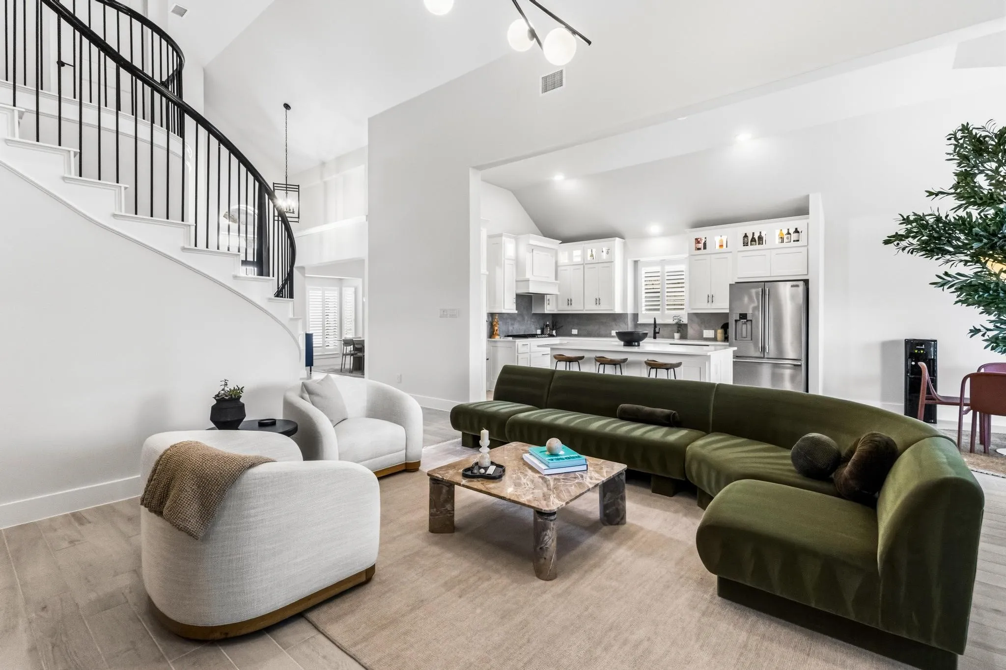 Spacious living area featuring light wood-finish flooring and a curved staircase with black metal balusters