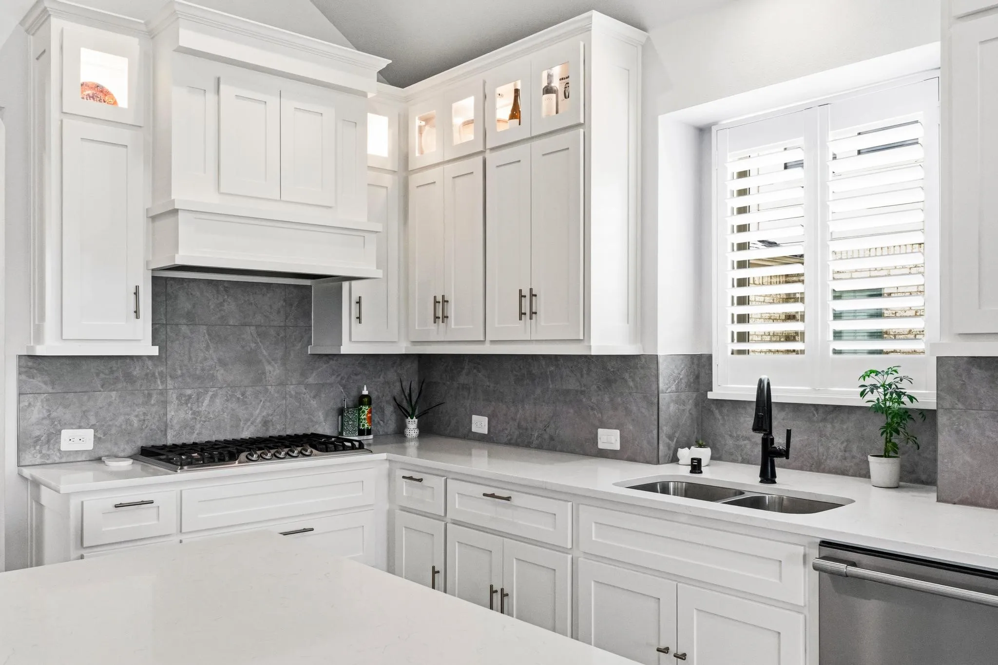 Modern kitchen featuring white cabinetry, quartz countertops, a gas cooktop, and a double basin sink with a matte black faucet