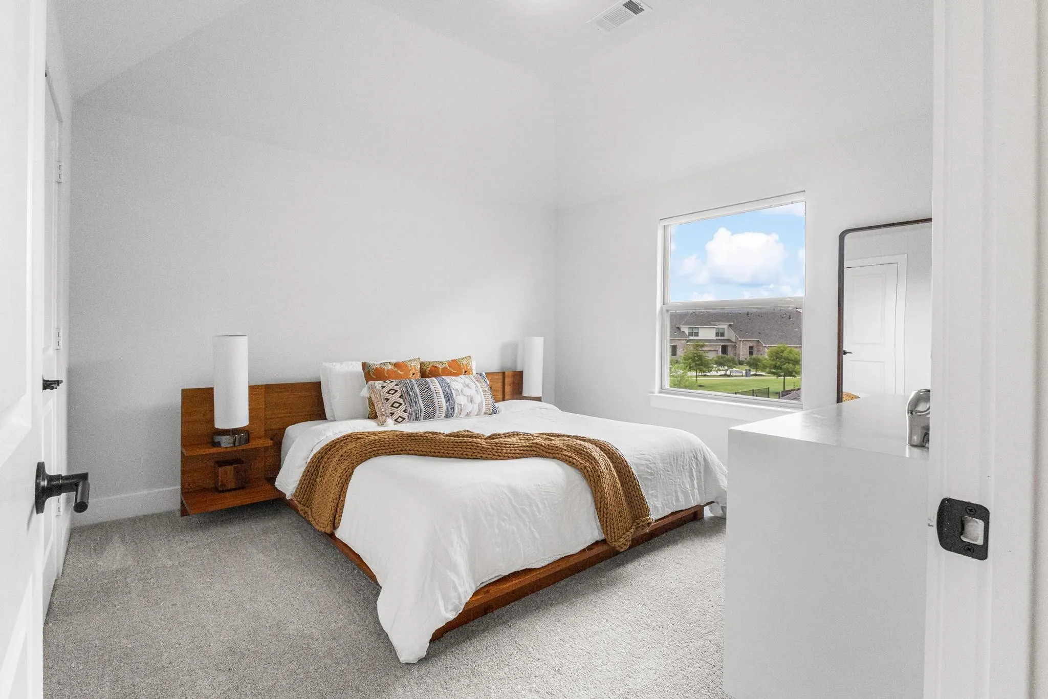 Bedroom featuring vaulted ceilings, light gray carpeting, and a large window with white trim
