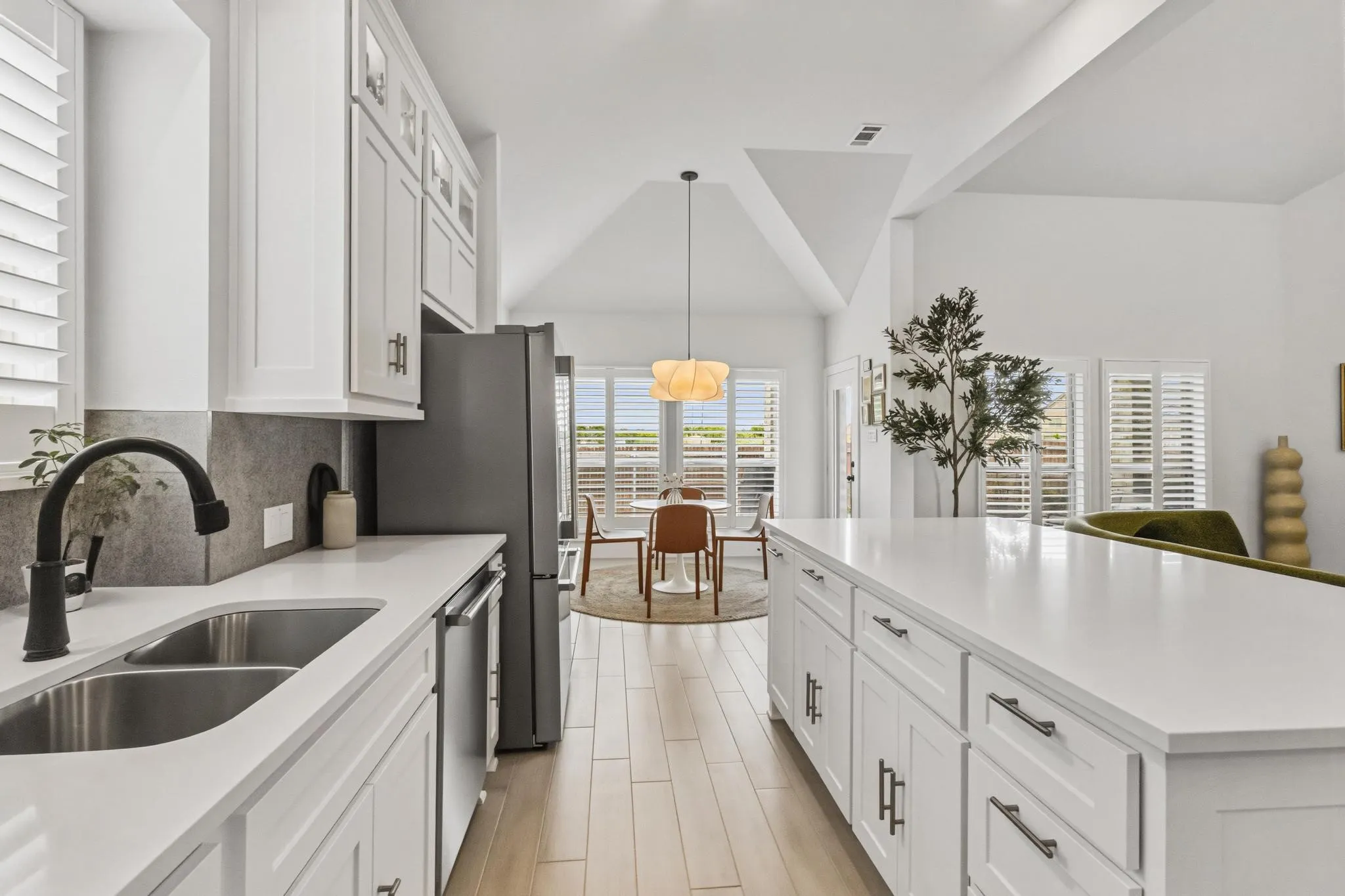 Kitchen with white shaker cabinetry, stainless steel appliances, and light wood-finish flooring