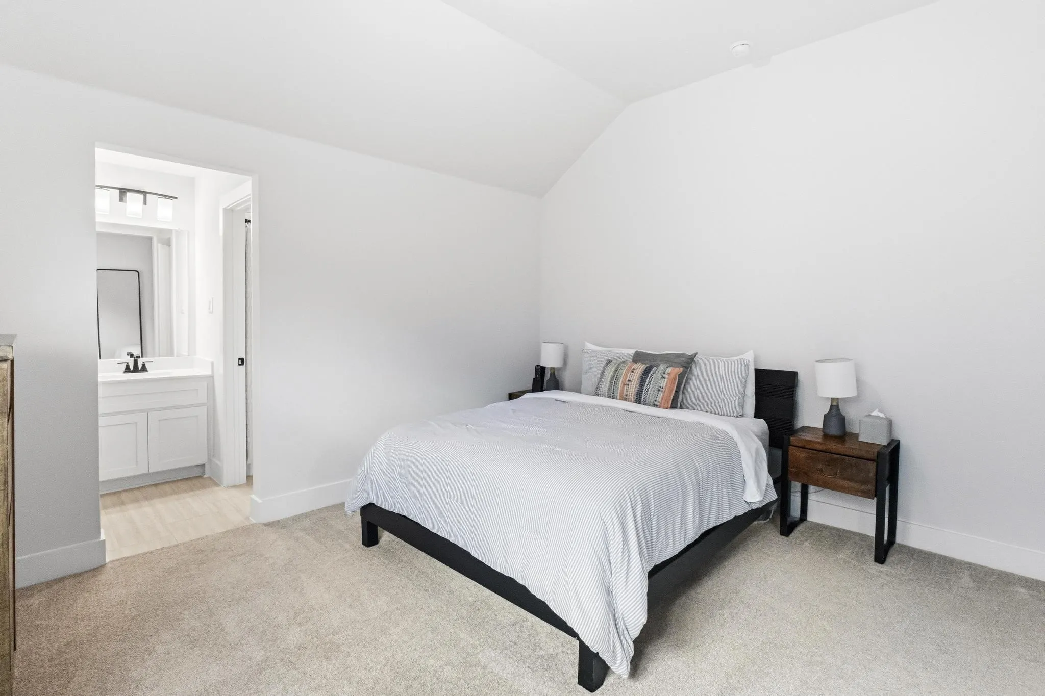 Carpeted bedroom with vaulted ceiling and white walls