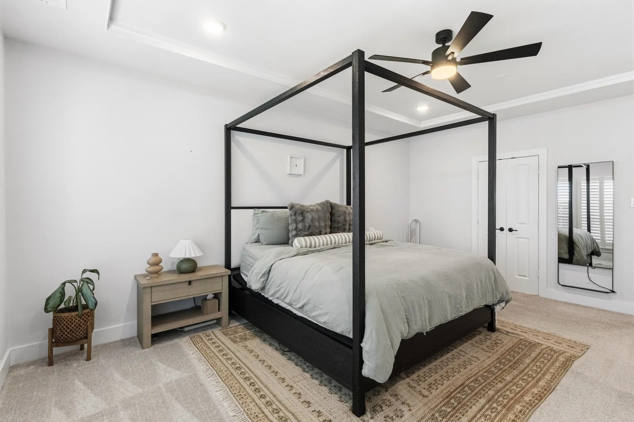 Carpeted bedroom featuring a black ceiling fan with integrated lighting, recessed lighting, and a tray ceiling