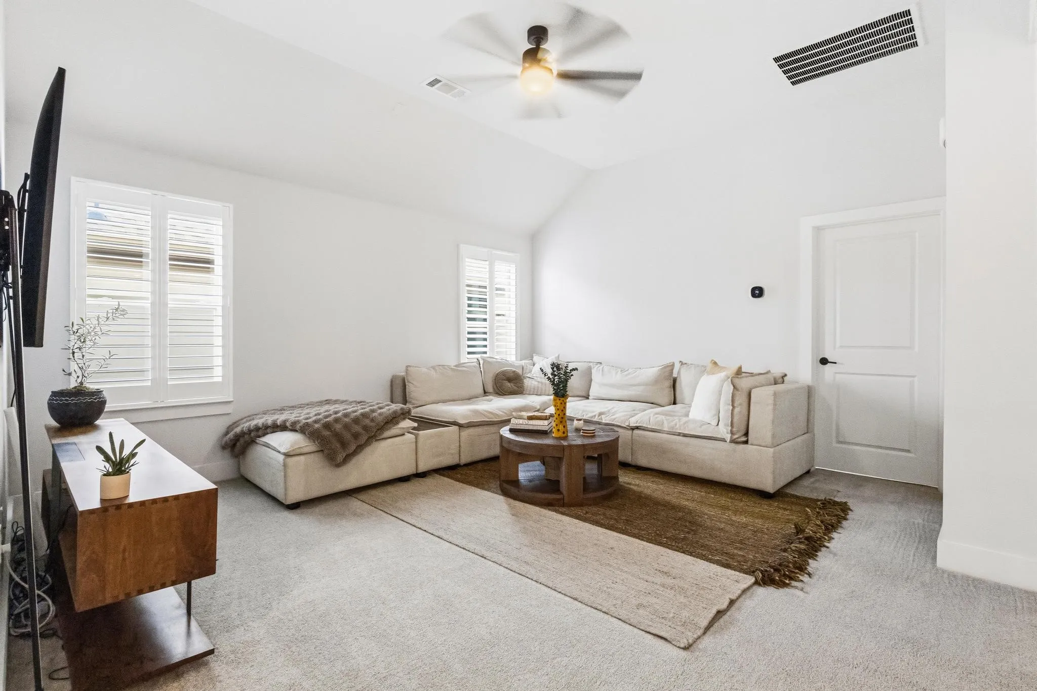 Vaulted ceiling living space featuring plantation shutters, recessed lighting, and a ceiling fan
