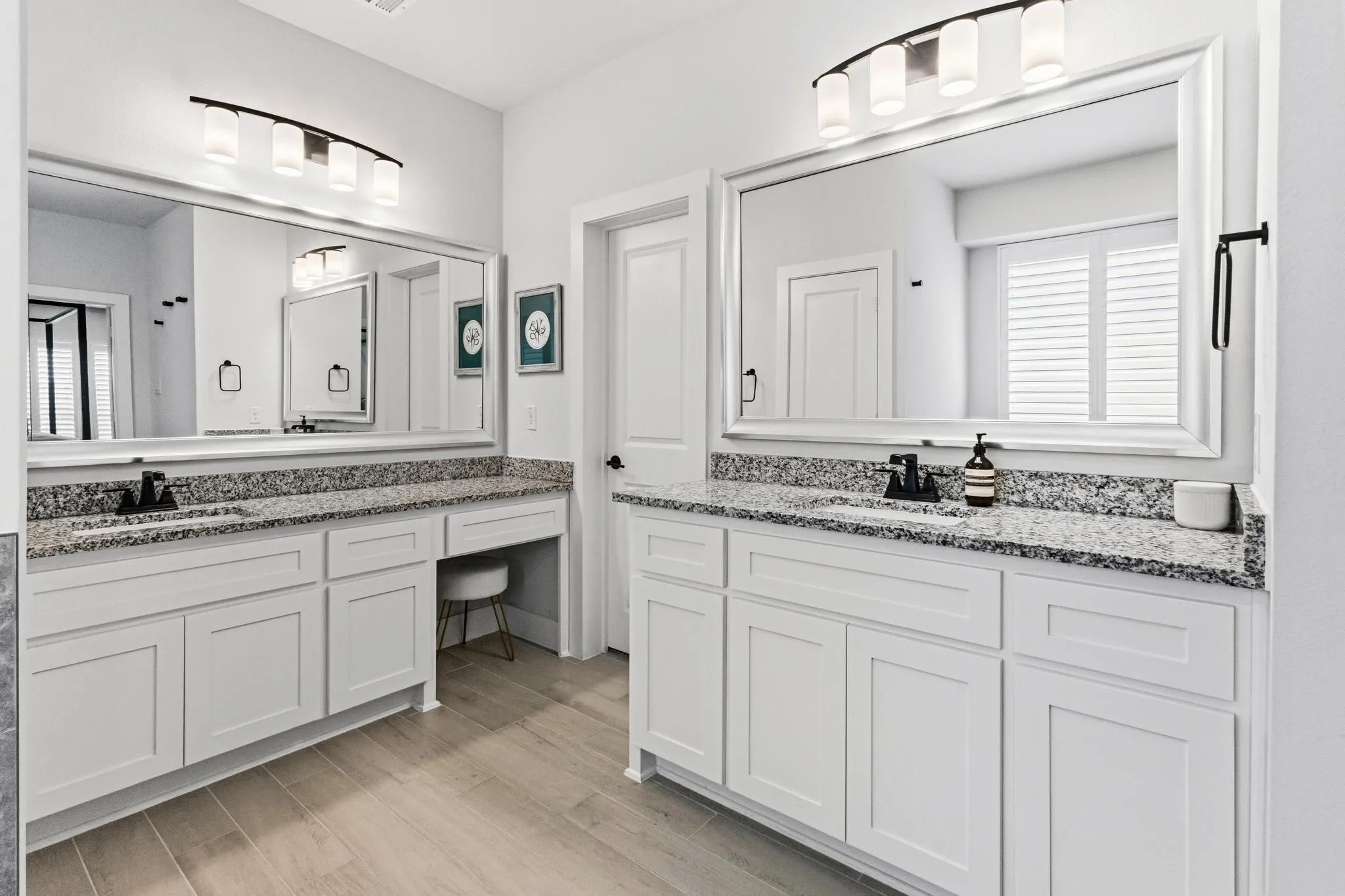 Dual vanity with white cabinetry, speckled stone countertops, and wood-finish flooring