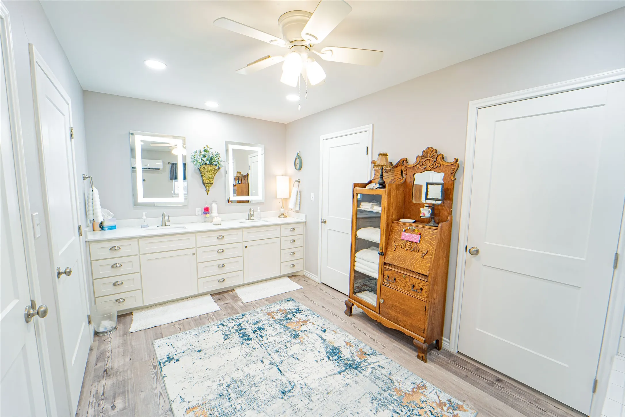 Double vanity with white cabinetry, integrated sinks, and illuminated mirrors
