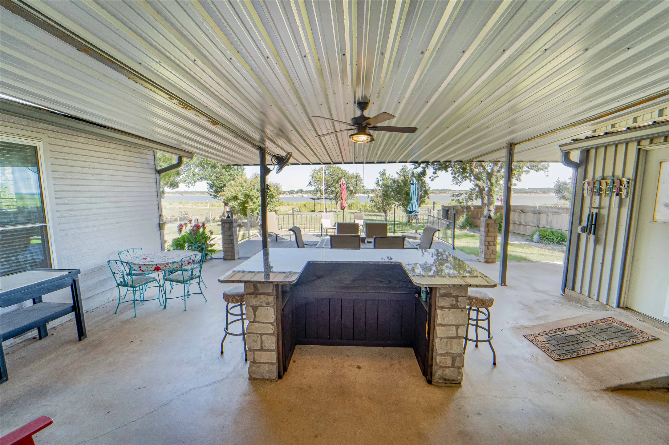 Beautiful Lake views from an Expansive covered patio featuring a built-in bar with stone accents and a polished countertop, lots of room for relaxing and entertaining!