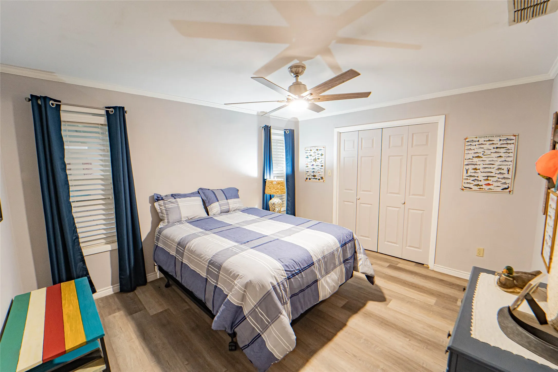 Large Guest BedRoom featuring wood-finish flooring, a ceiling fan with integrated lighting, and crown molding