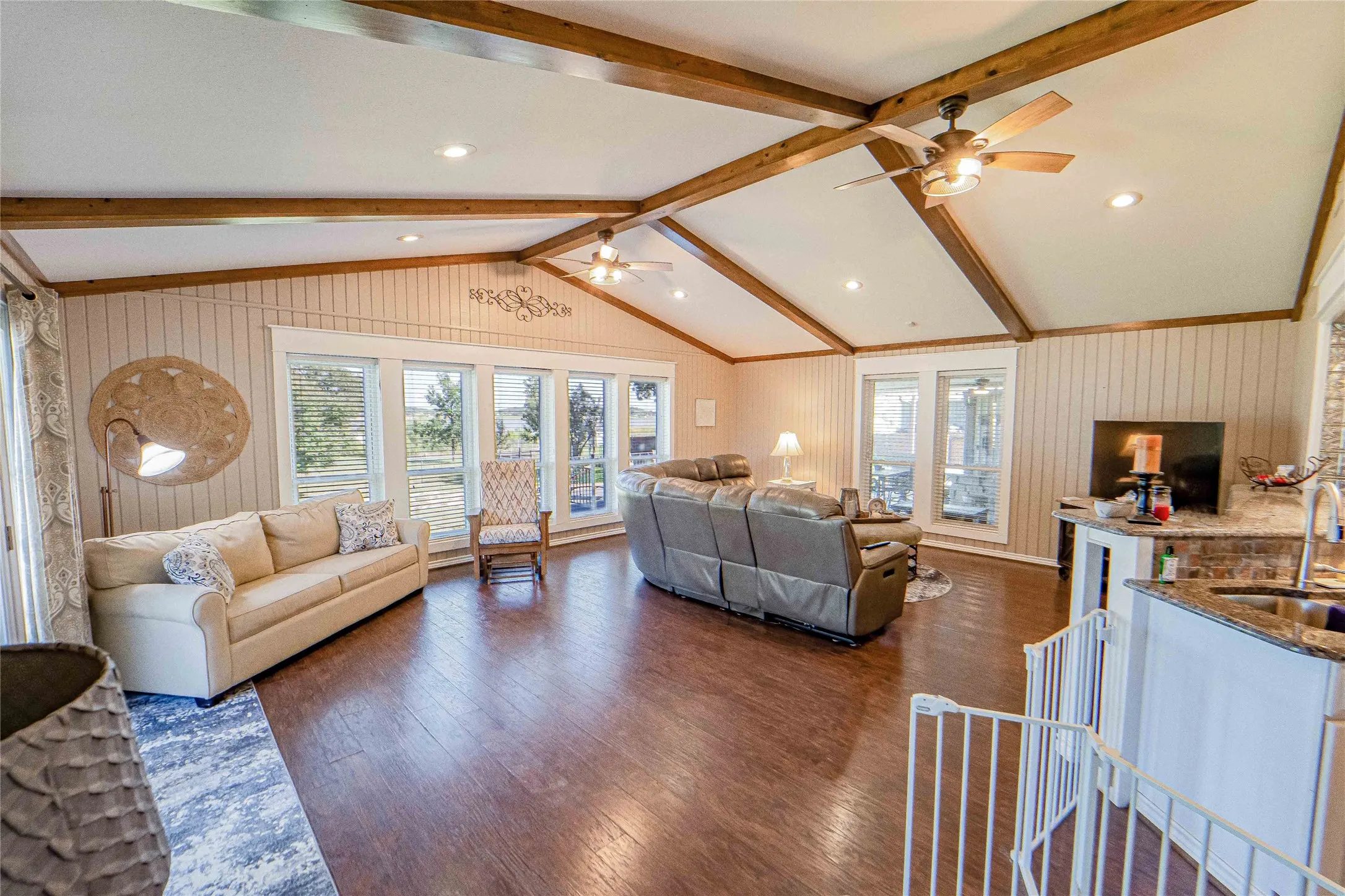 Open Conc[pet, Lake Views-Spacious living area featuring exposed wood beams, vaulted ceilings, wood-finish flooring, and ample natural light from multiple windows