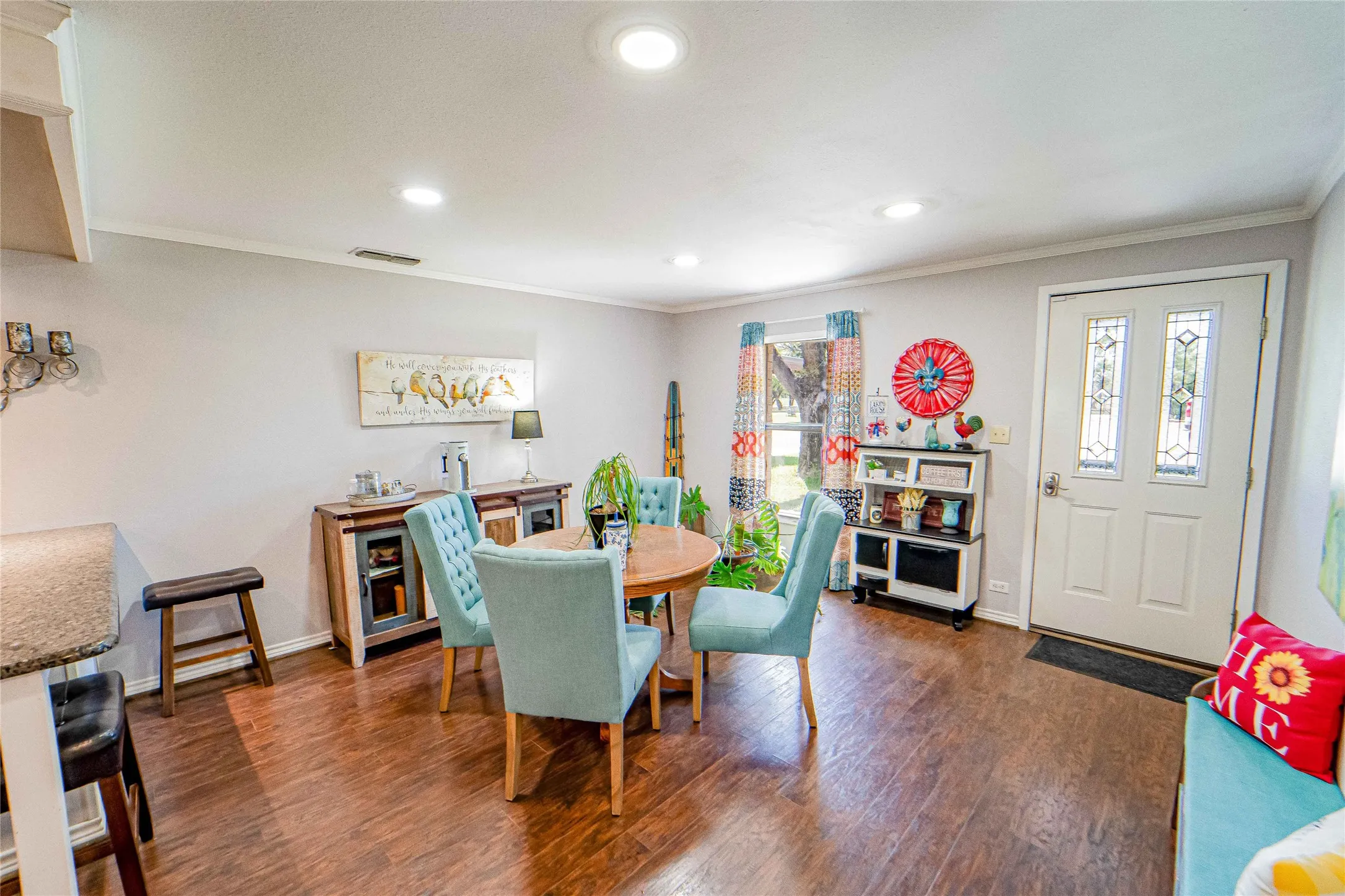 Dining arear with granite topped breakfast bar, Wood-finish flooring throughout, complemented by a white entry door with decorative glass inserts
