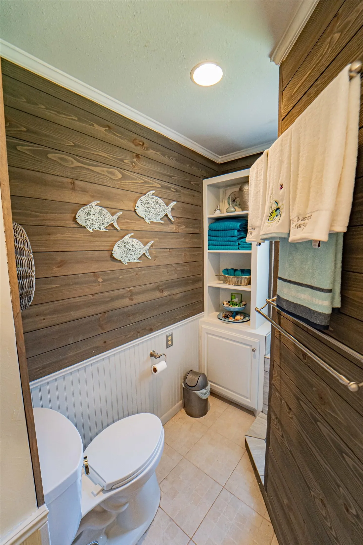 Powder room featuring wood-finish wall paneling, white beadboard wainscoting, and tile flooring
