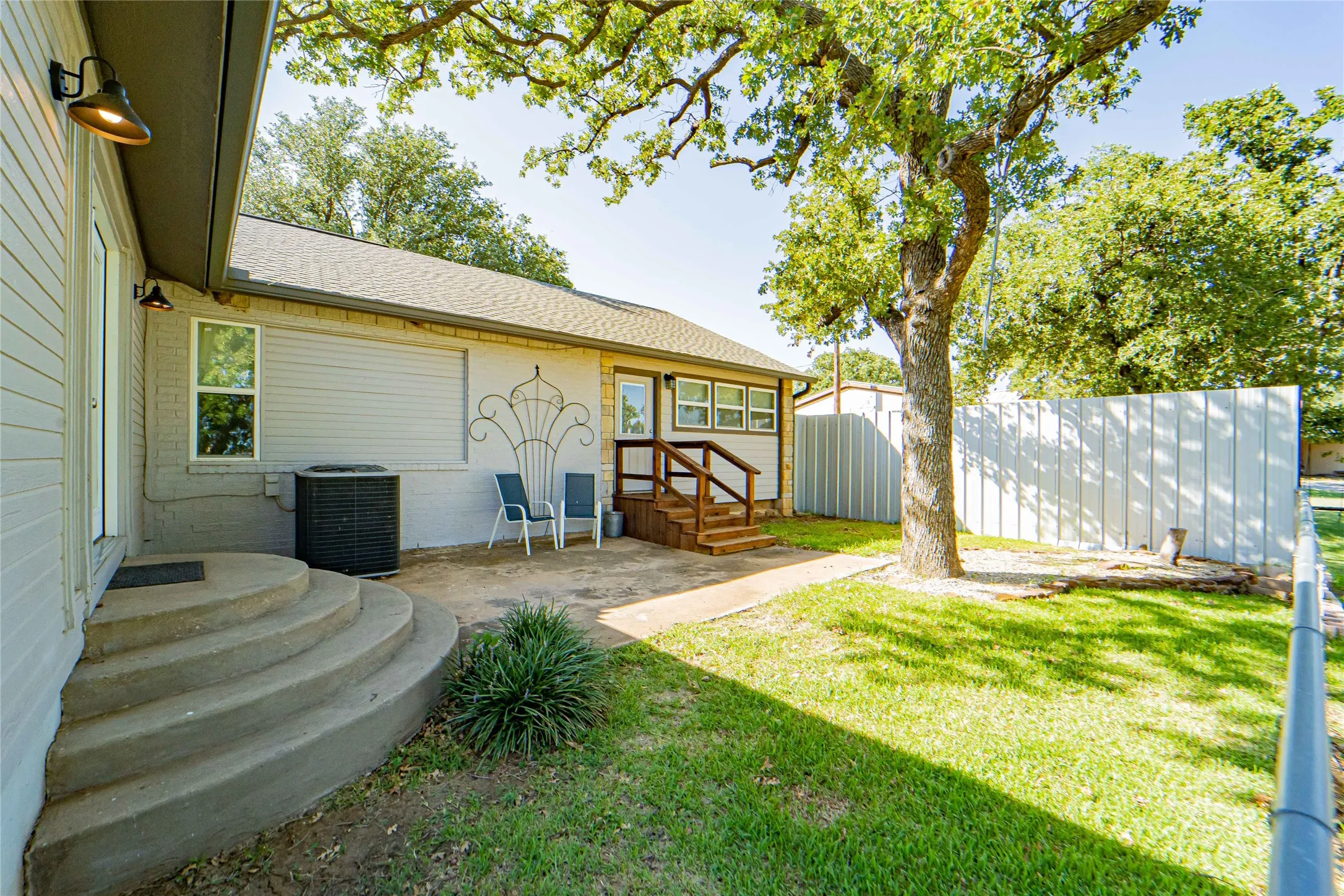 Private Backyard patio area featuring mature shade tree, concrete steps, and a privacy fence-perfect for morning coffee!
