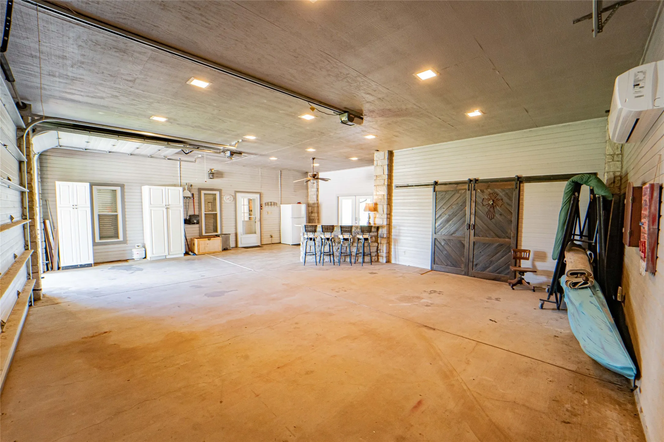 Double this attached garage as an entertaining area/gaming room with mini split, granite topped bar, cozy fireplace, room for extra fridge and freezer with lots of added storage-Expansive open space with a concrete floor and recessed lighting