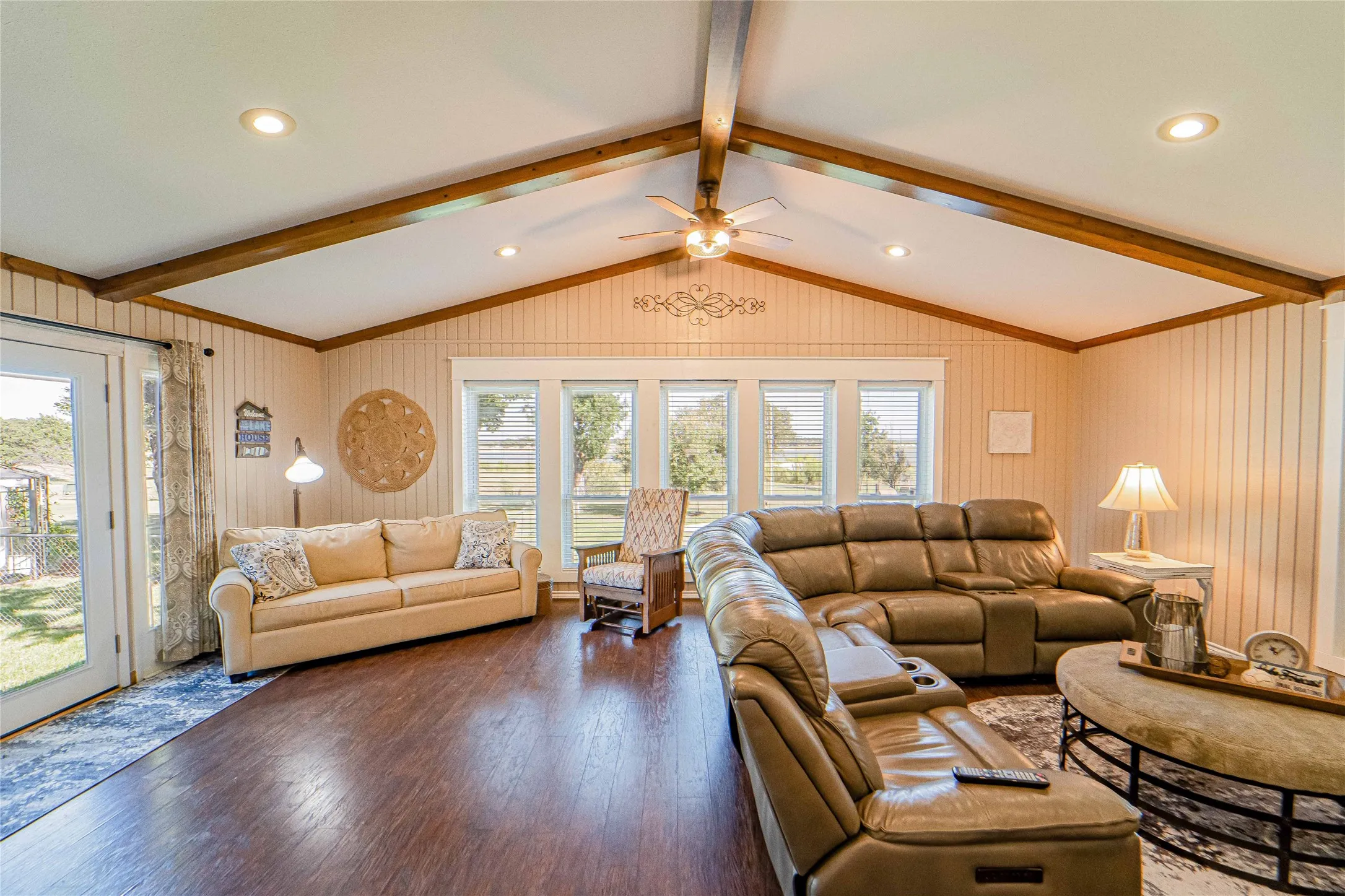 Large and open Living area, views from all three angles-Lake, covered patio area and side yard create wonderful natural light-Vaulted ceiling with exposed wood beams and recessed lighting