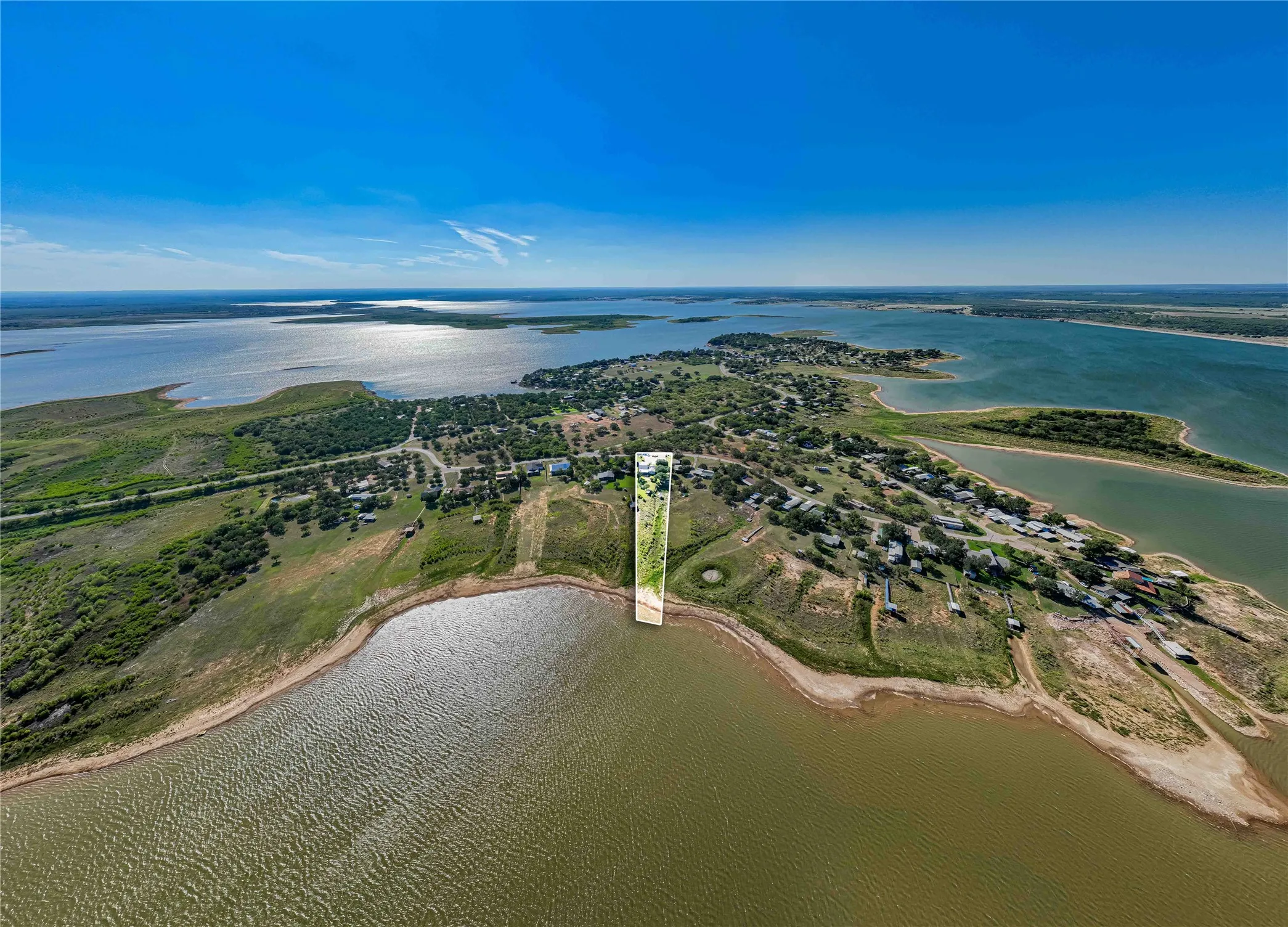 Waterfront property featuring extensive water frontage, a large land parcel, established surrounding properties, and clear skies